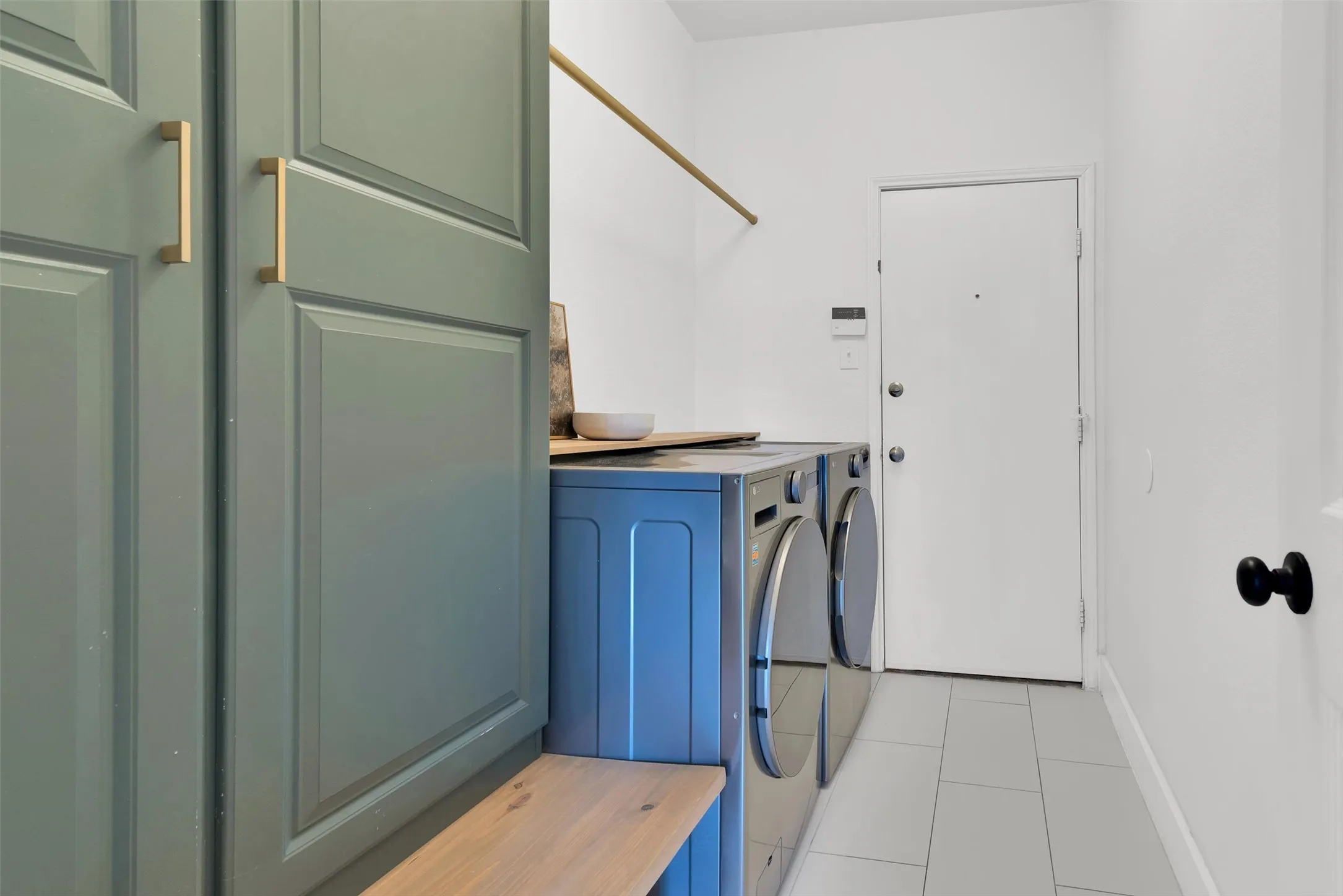 Built-in cabinetry with gold-tone hardware, wood-tone countertop, and light gray tile flooring