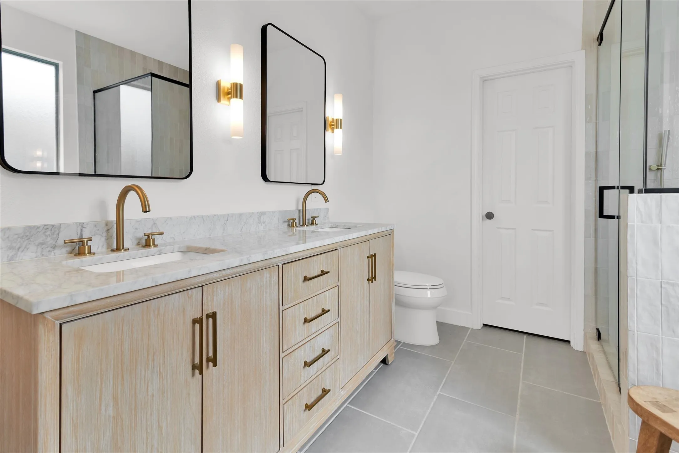 Dual vanity with light wood-finish cabinetry and gold-tone hardware