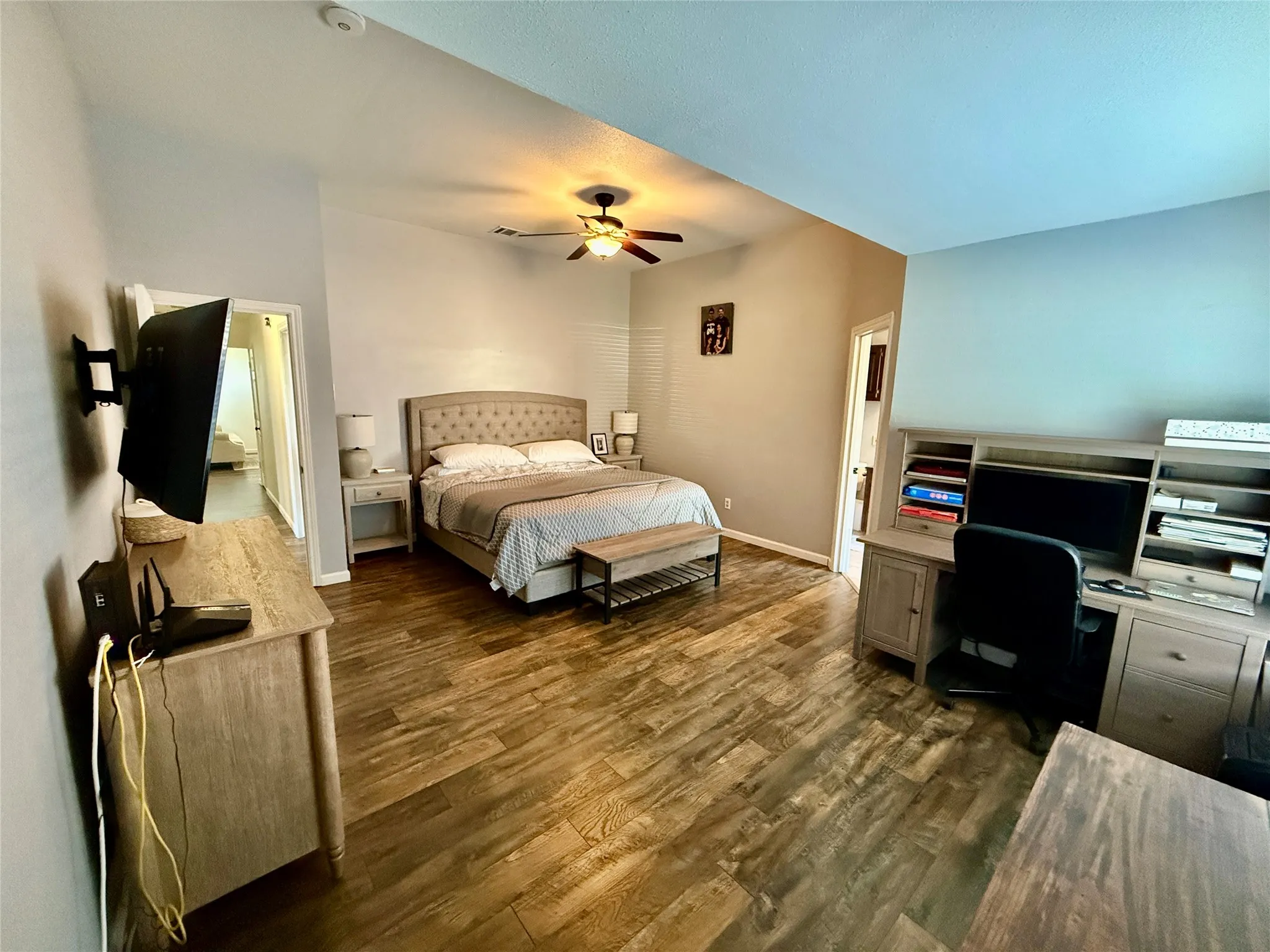 Wood-finish flooring throughout, ceiling fan with integrated lighting, and built-in desk cabinetry