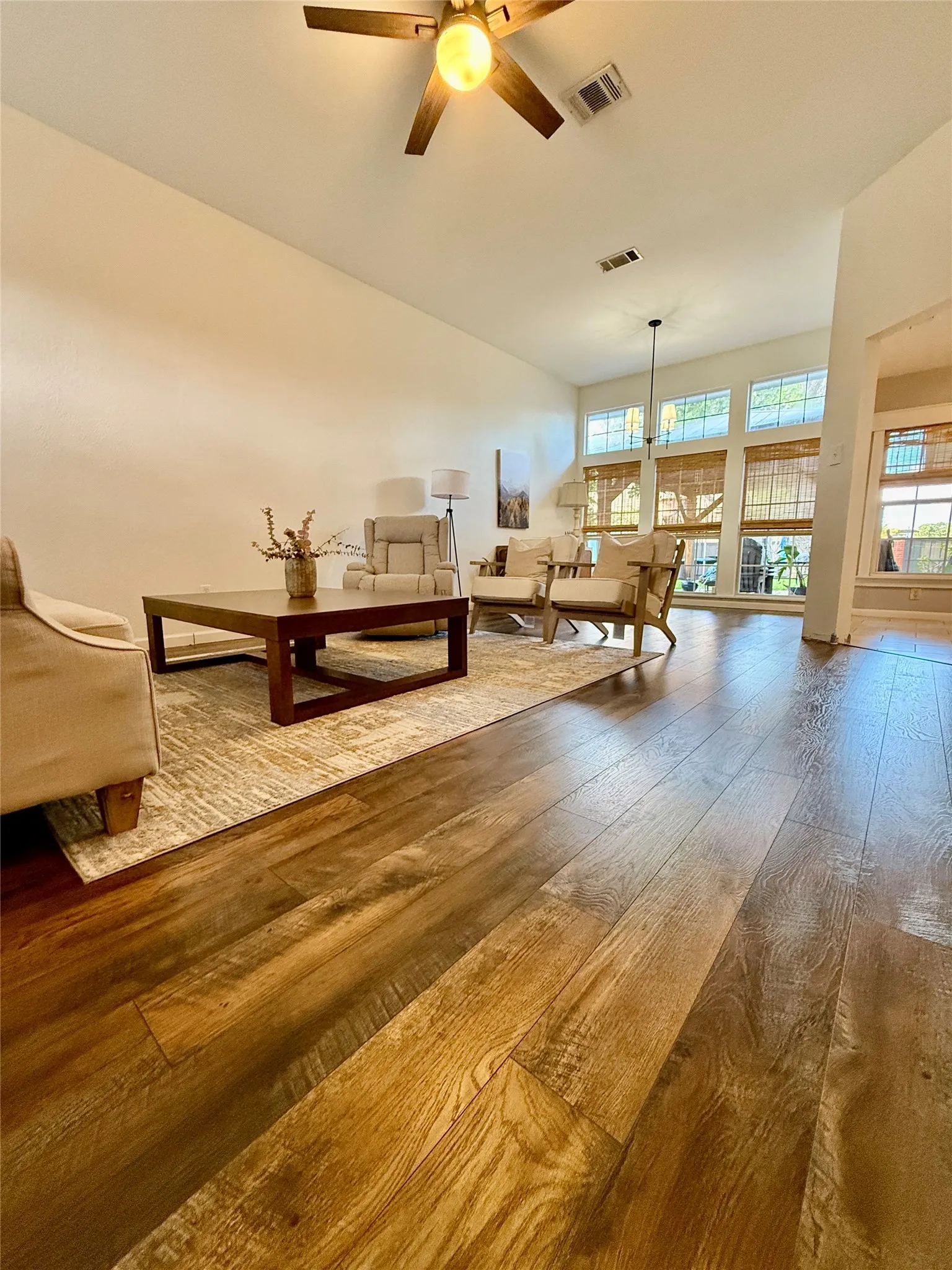 Vaulted ceilings with a ceiling fan, wood-finish flooring, and ample natural light from multiple windows
