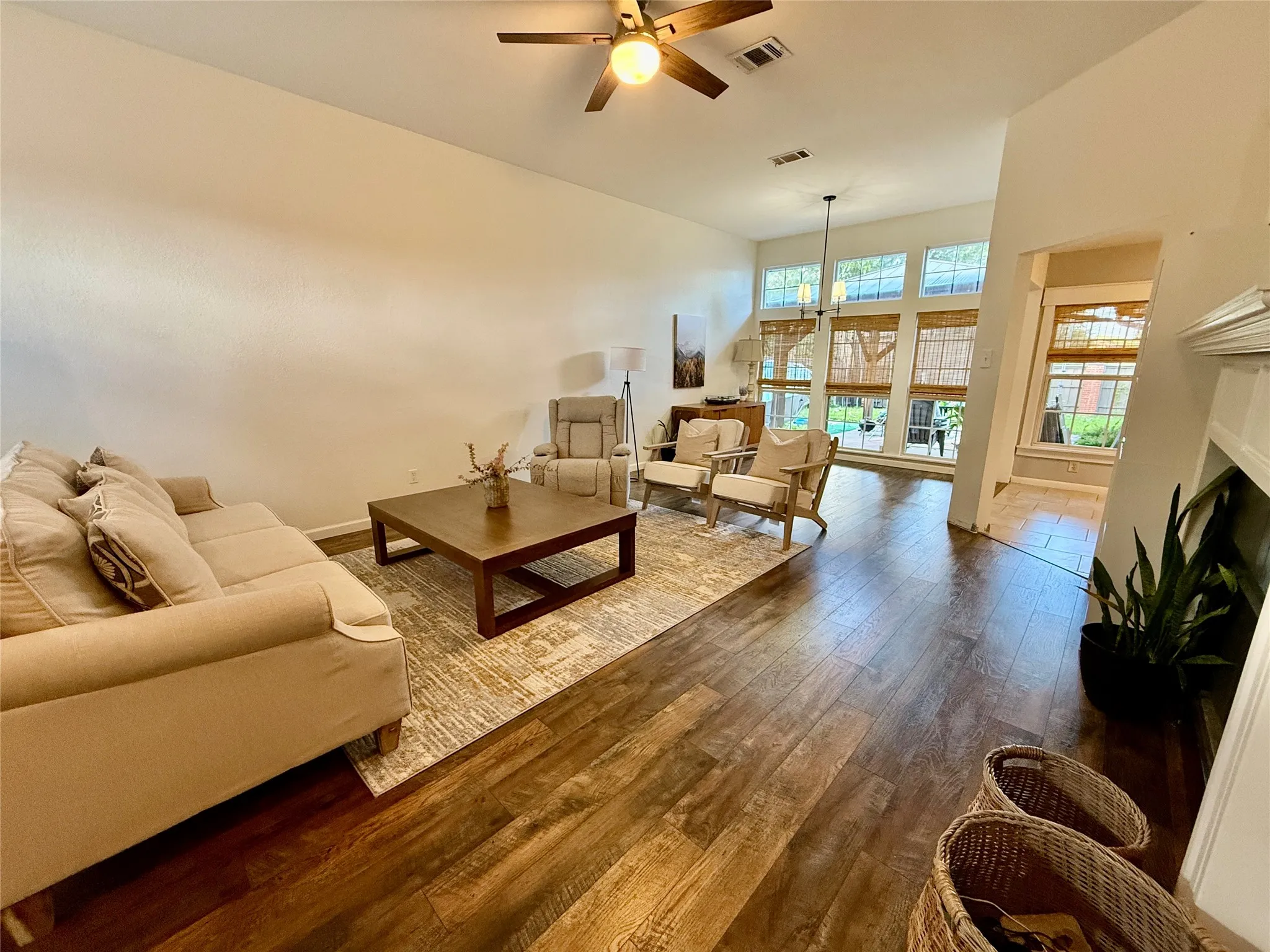 Vaulted ceiling with a ceiling fan, wood-finish flooring, and ample natural light from multiple windows
