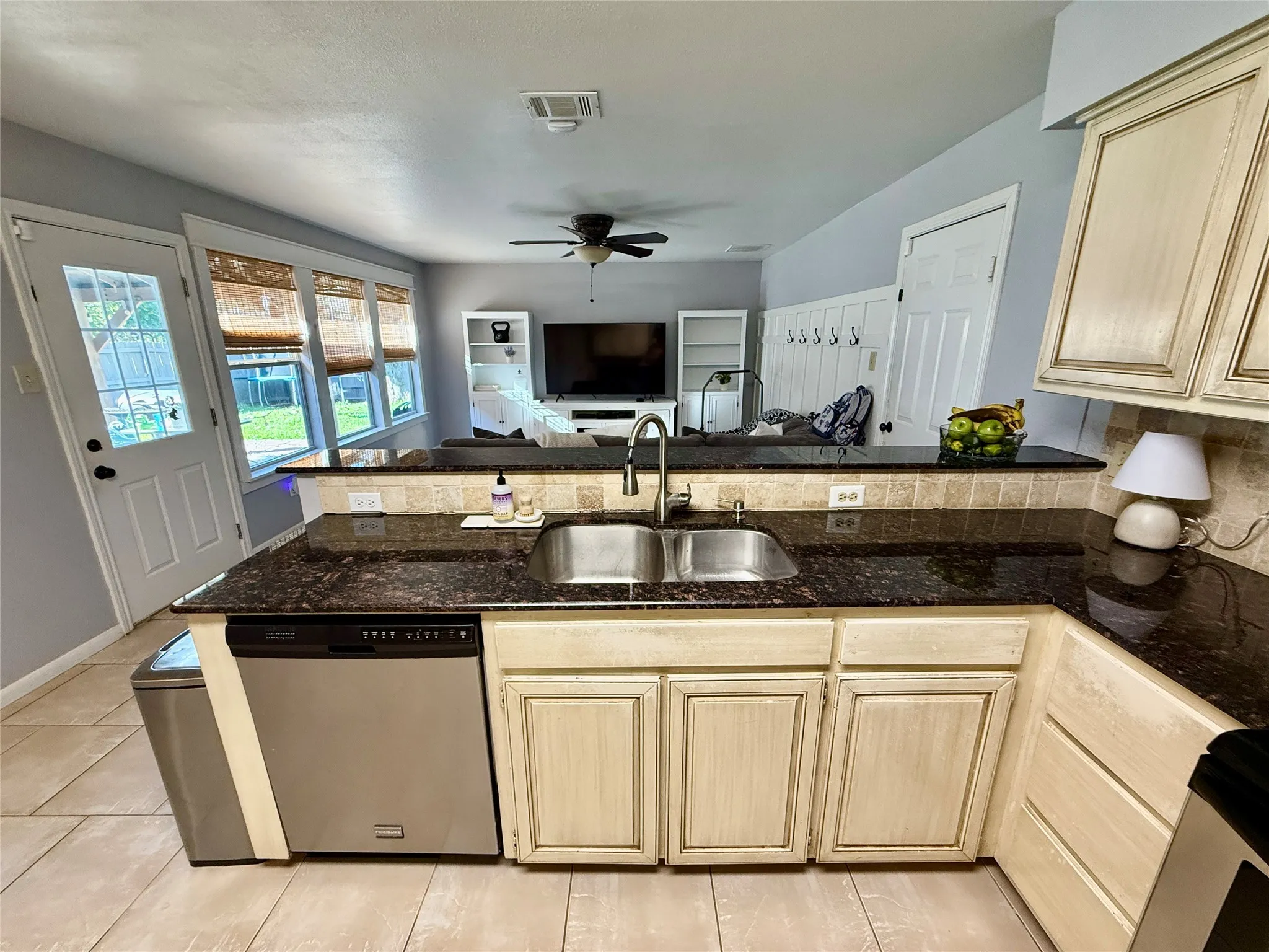 Kitchen with dual basin stainless steel sink, dark granite countertops, and light-toned cabinetry