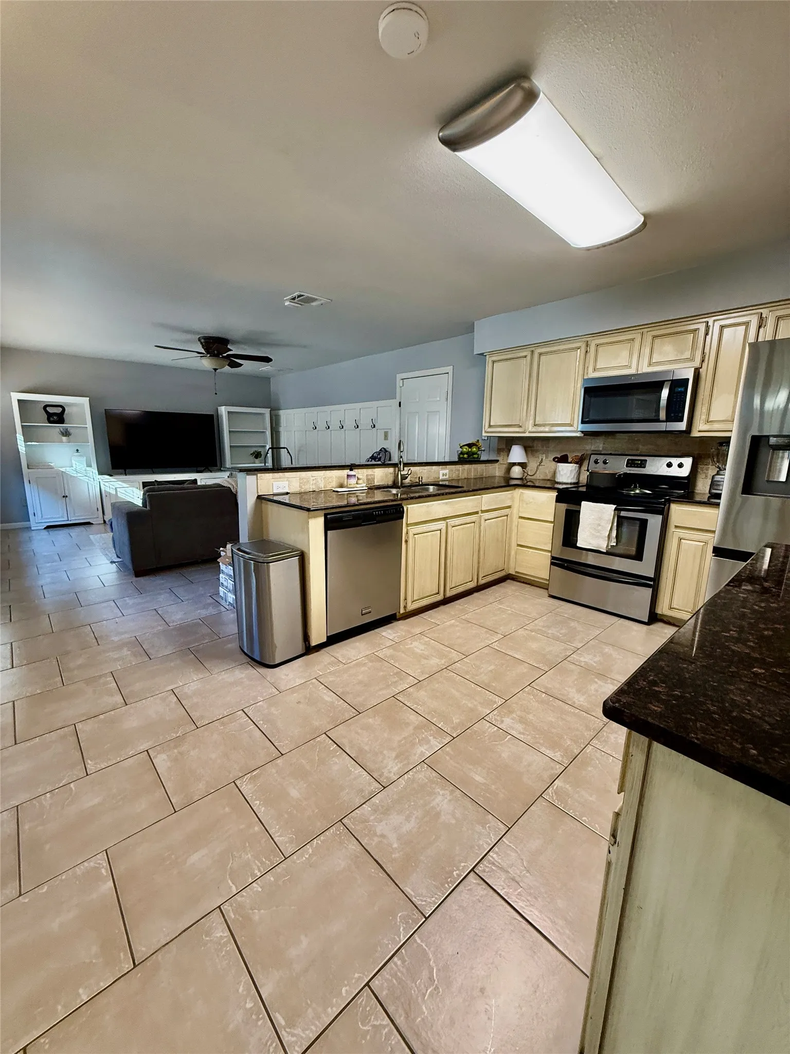 Kitchen with tile flooring, dark countertops, and stainless steel appliances