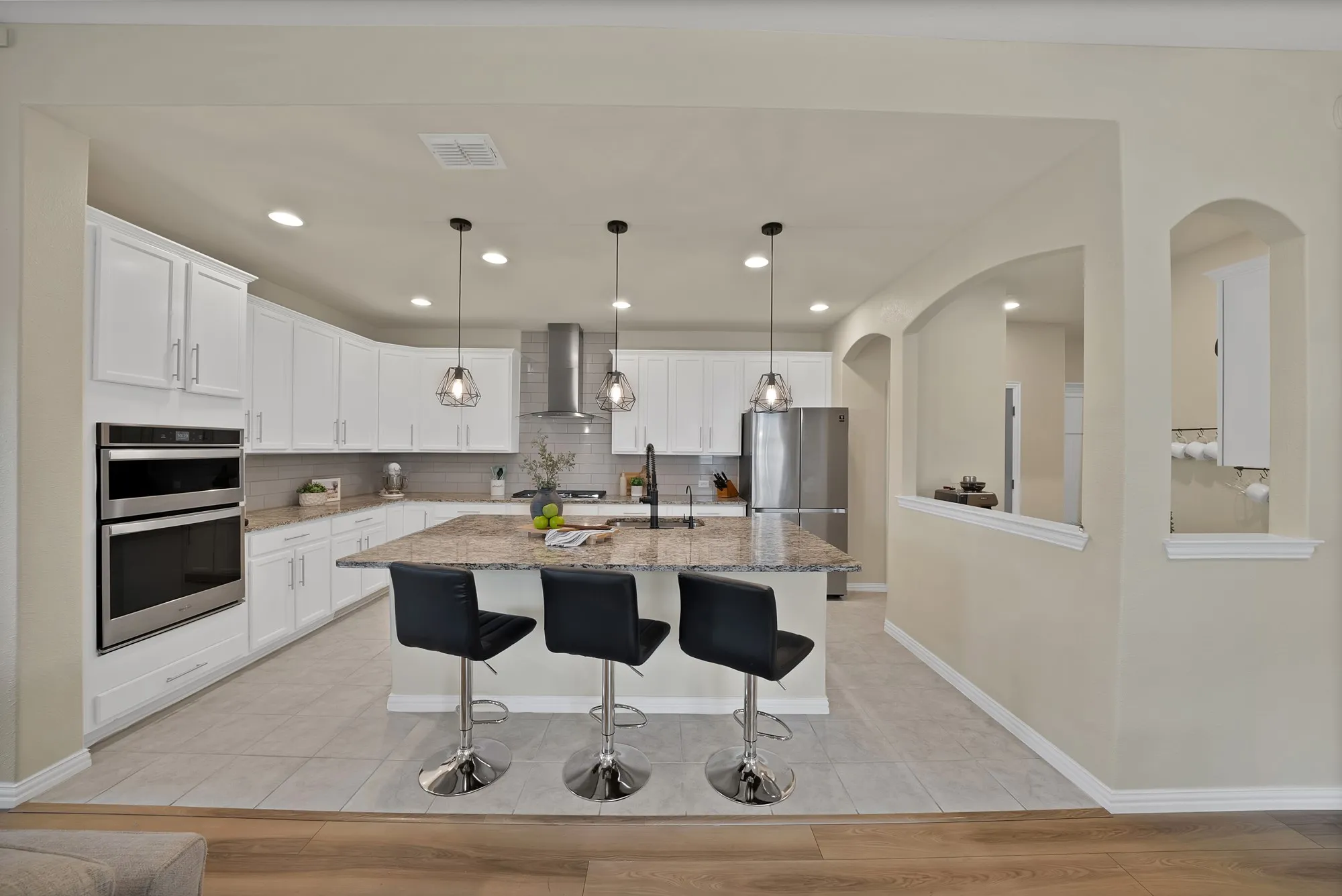 Gourmet kitchen with white cabinetry, stainless steel appliances, a stone countertop island, and pendant lighting