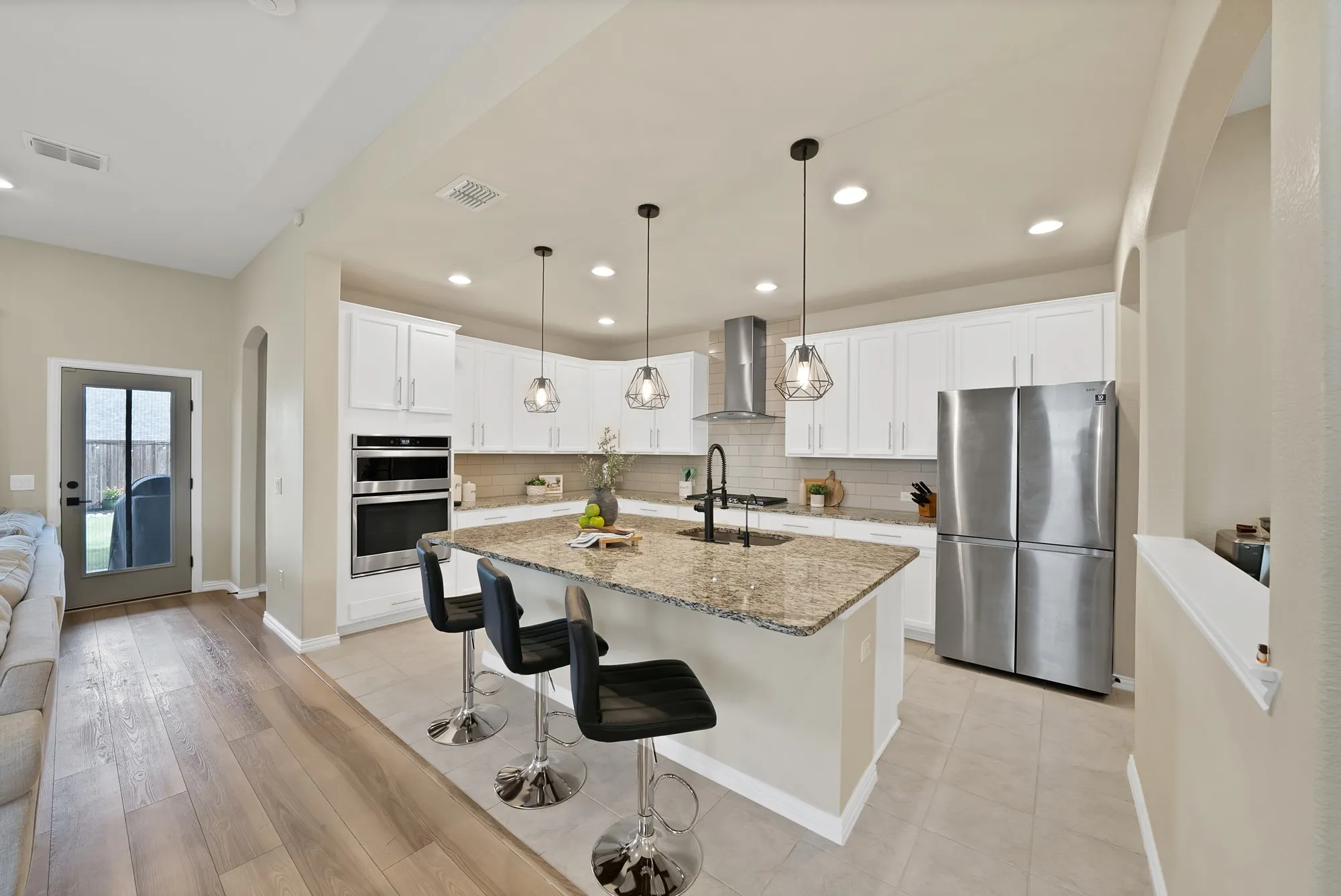Kitchen featuring a center island with bar seating, pendant lighting, stainless steel appliances, white cabinetry, and light-colored tile flooring