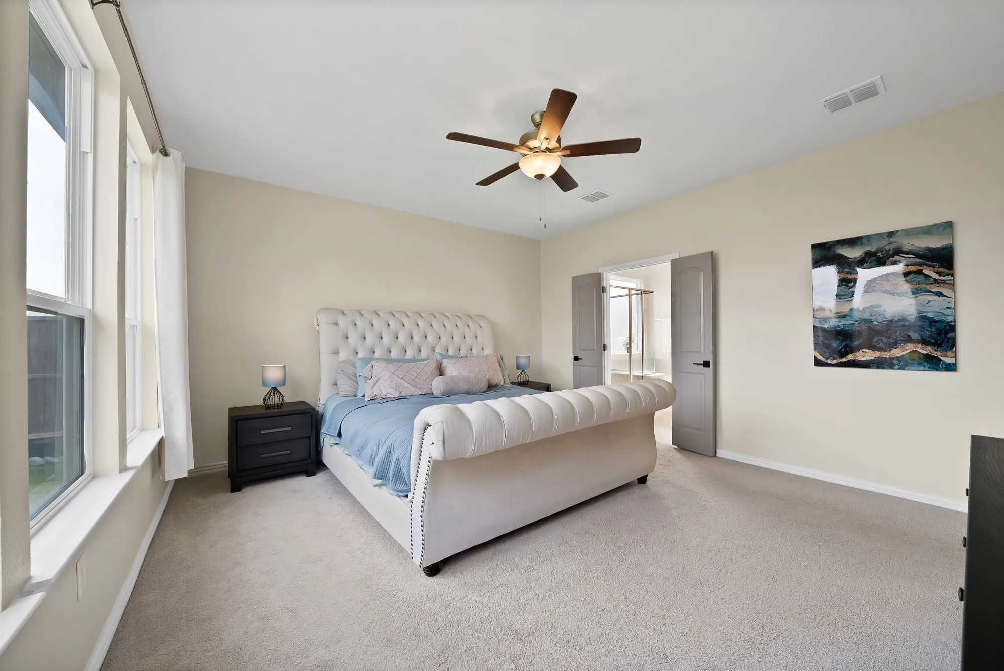 Plush carpet flooring, ceiling fan with integrated lighting, double windows with white trim, and light-toned walls