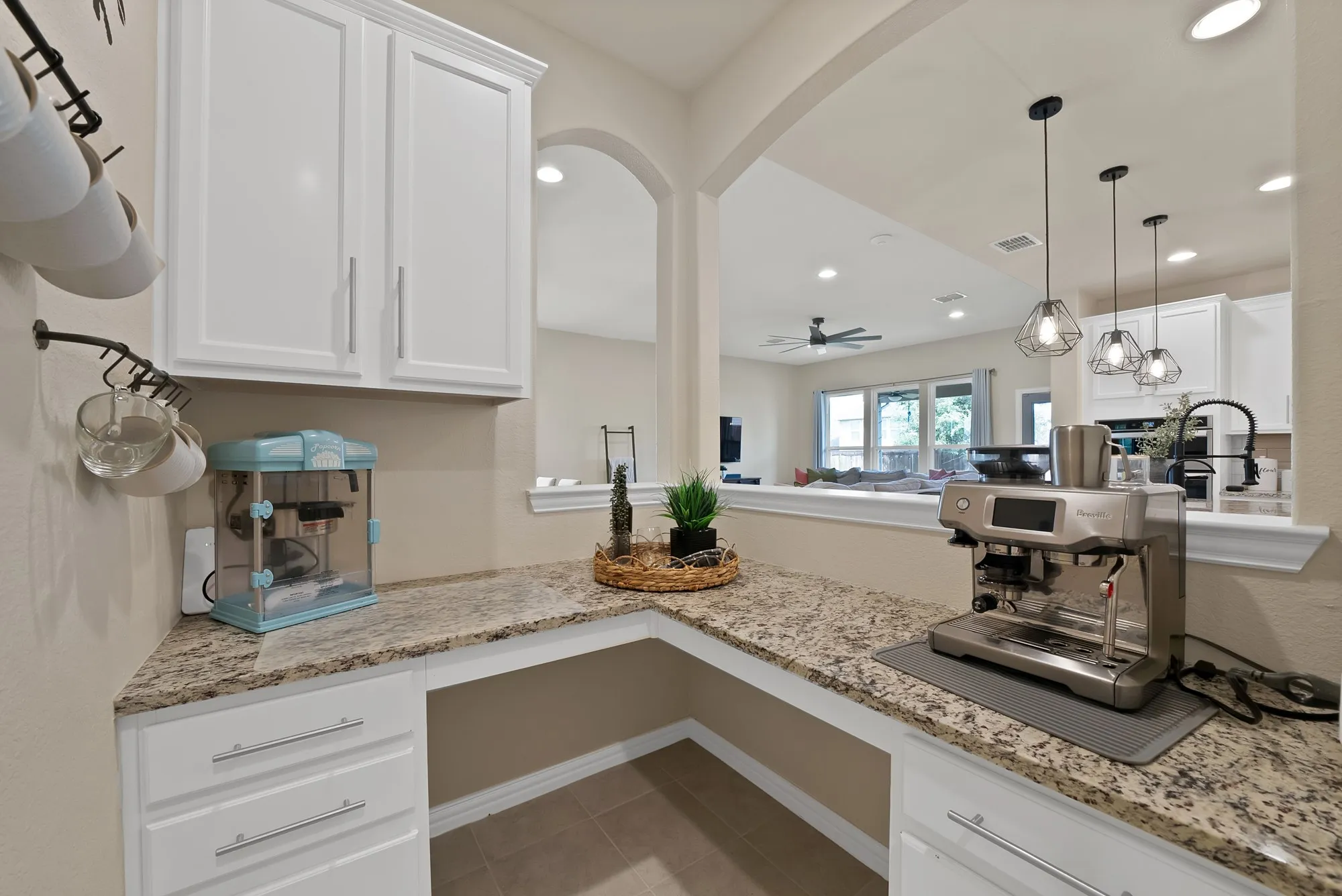 White cabinetry, stone-finish countertops, and an arched entryway to the main living area