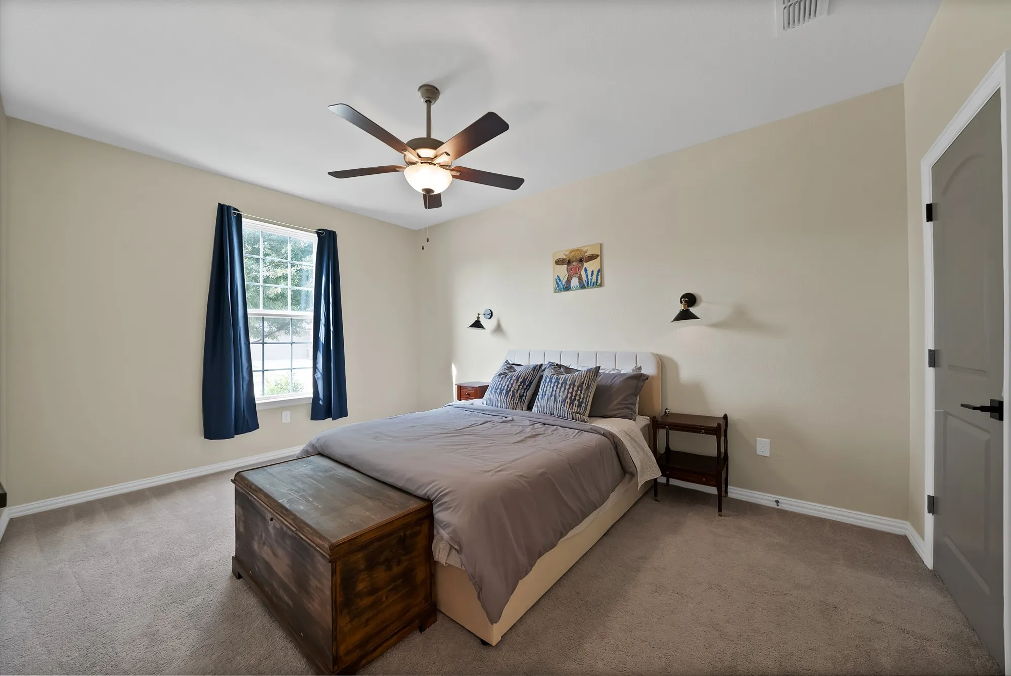 Recessed window with white trim, ceiling fan with integrated lighting, wall-mounted sconces, and neutral-toned carpeting