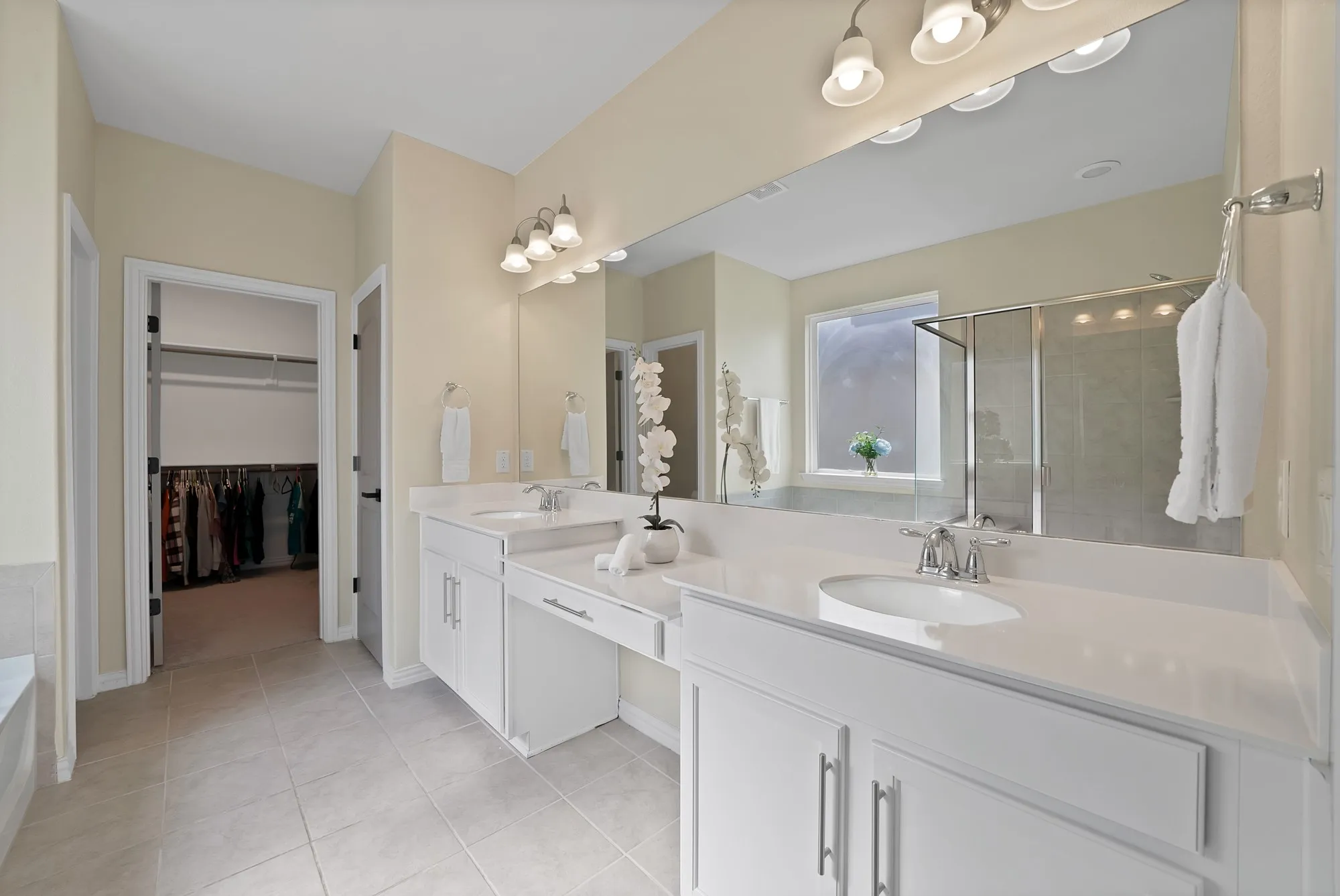 Dual vanity with white cabinetry, integrated sinks, chrome fixtures, and a large wall-mounted mirror