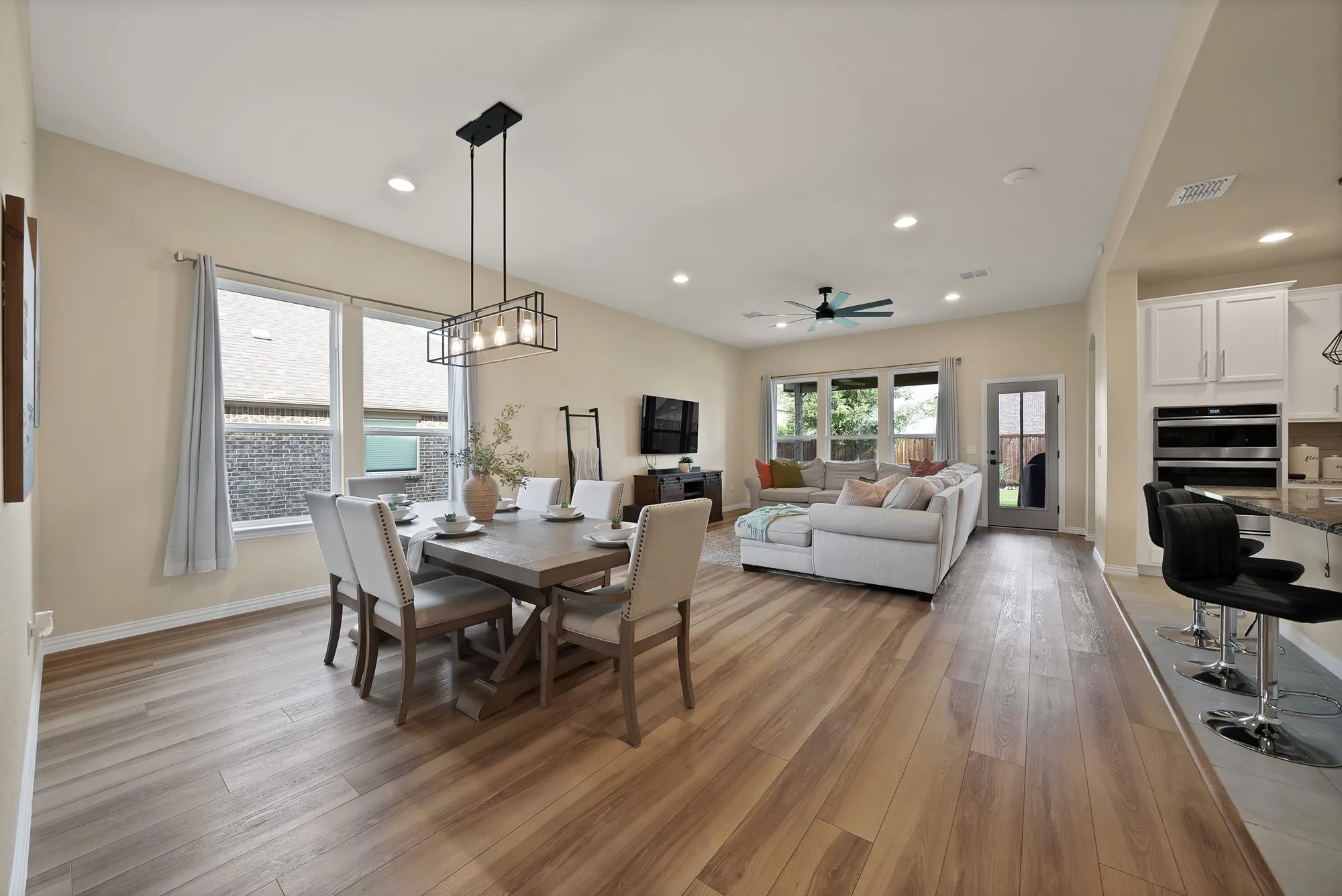 Wood-finish flooring throughout, recessed lighting, and a modern linear chandelier