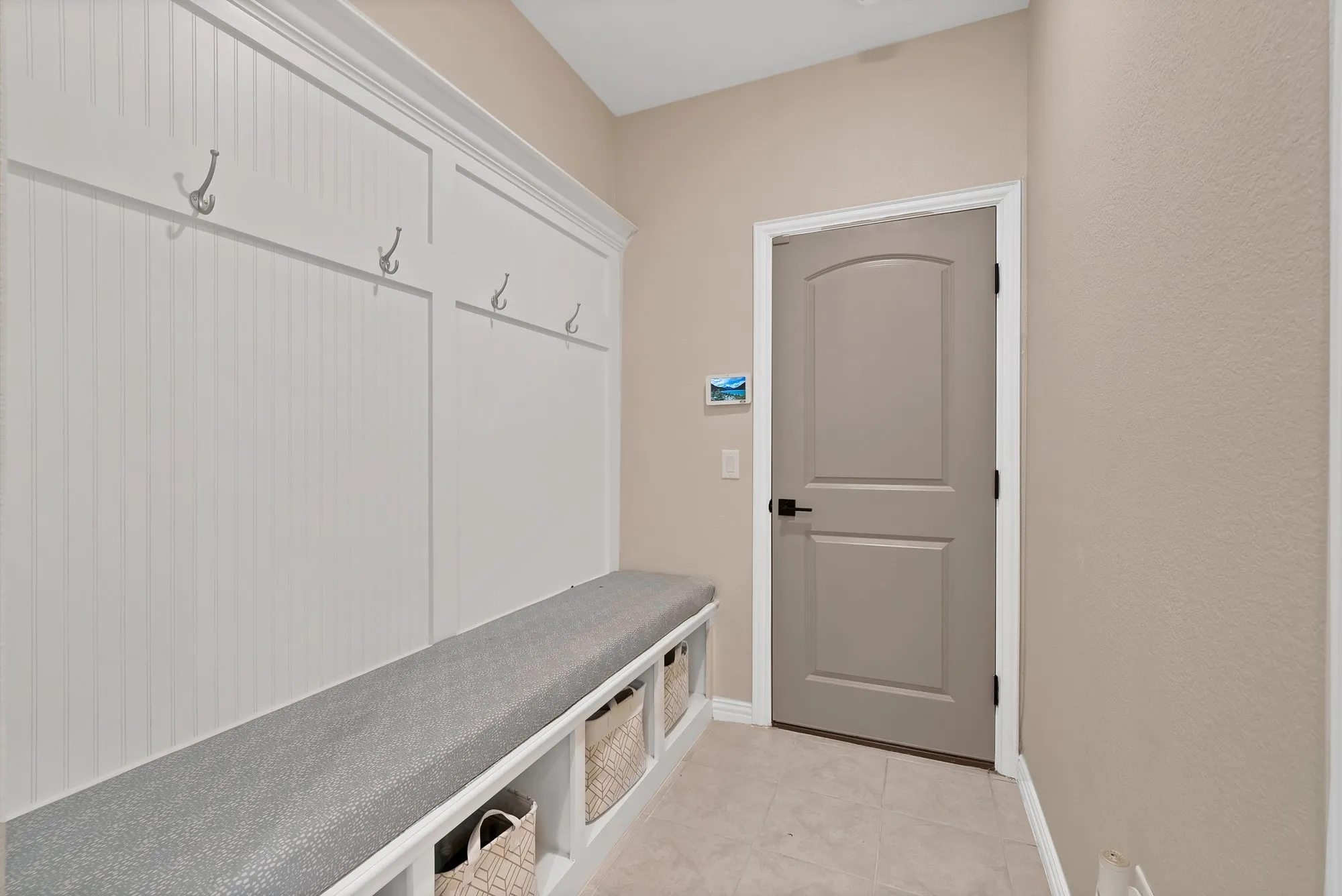 Built-in storage bench with cushion, beadboard wall paneling, and wall-mounted hooks