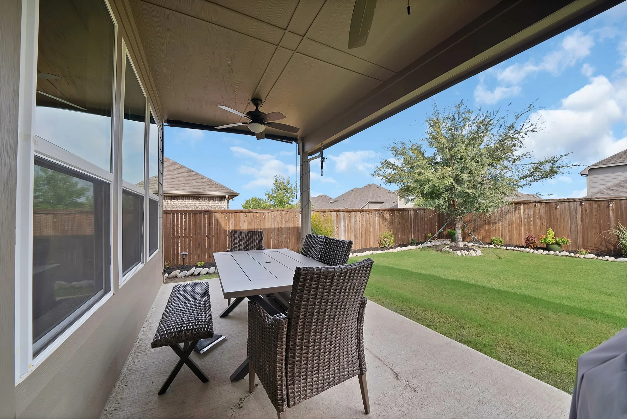 Covered patio with a ceiling fan, concrete flooring, and a large grassy area