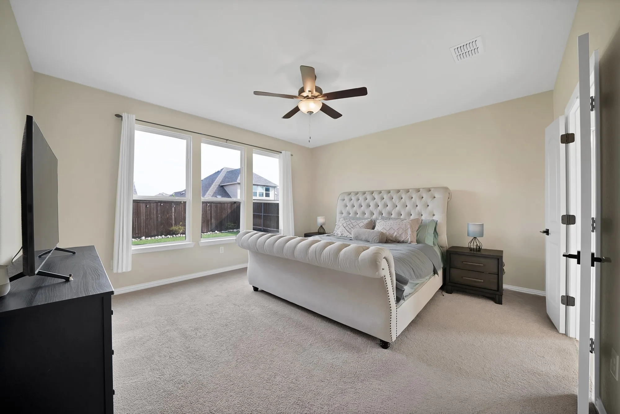 Vaulted ceilings, a dark wood-finish ceiling fan, recessed lighting, and three large windows