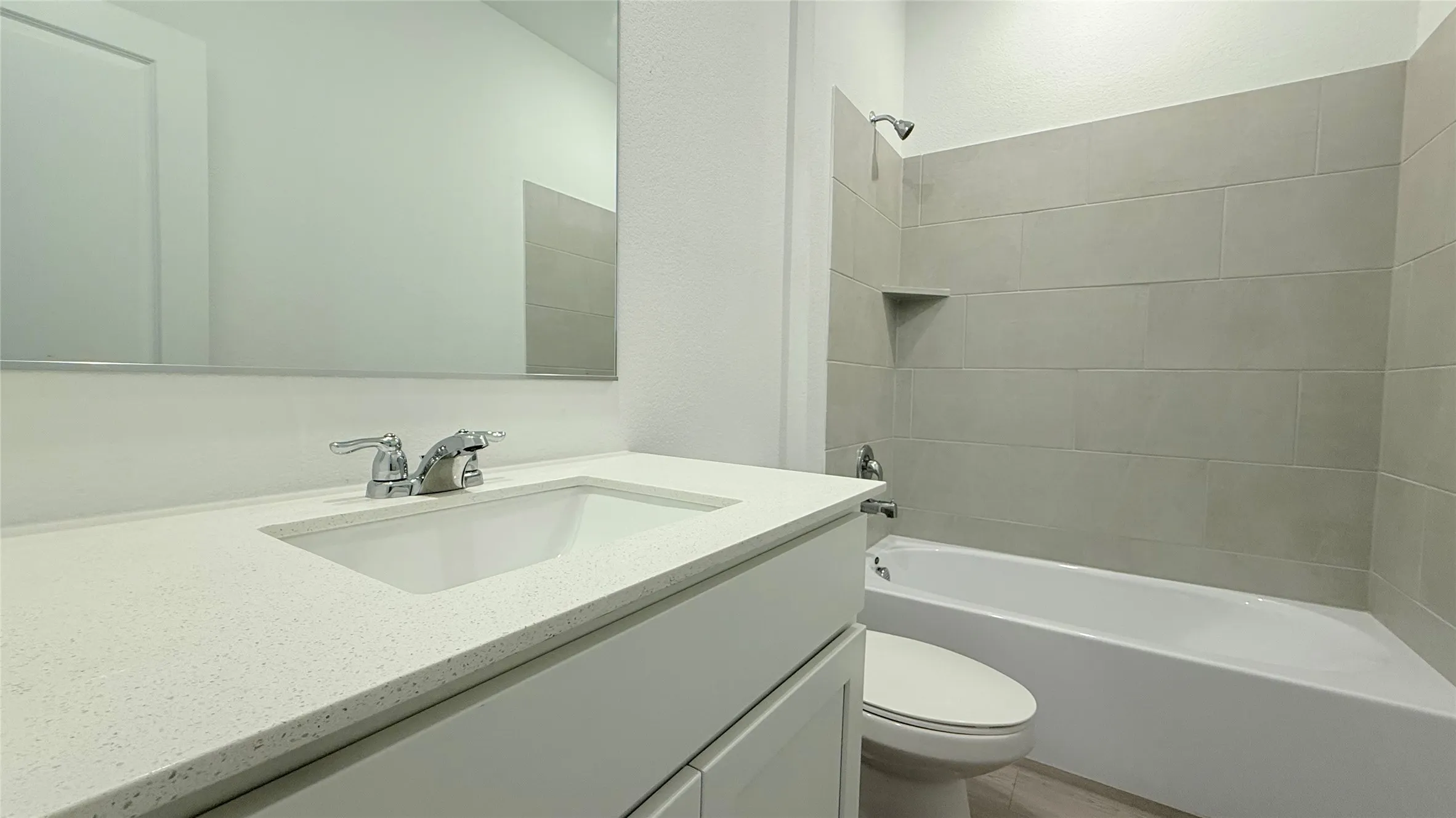 Bathroom featuring a white vanity with an integrated sink, polished chrome faucet, and full-width mirror