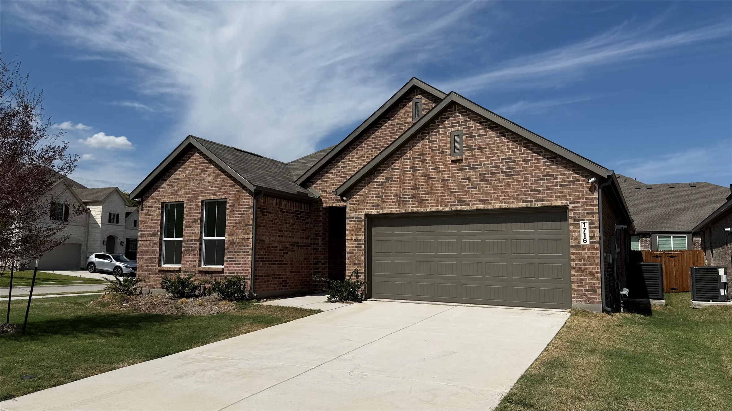 Brick exterior with a gabled roofline, concrete driveway, and attached two-car garage