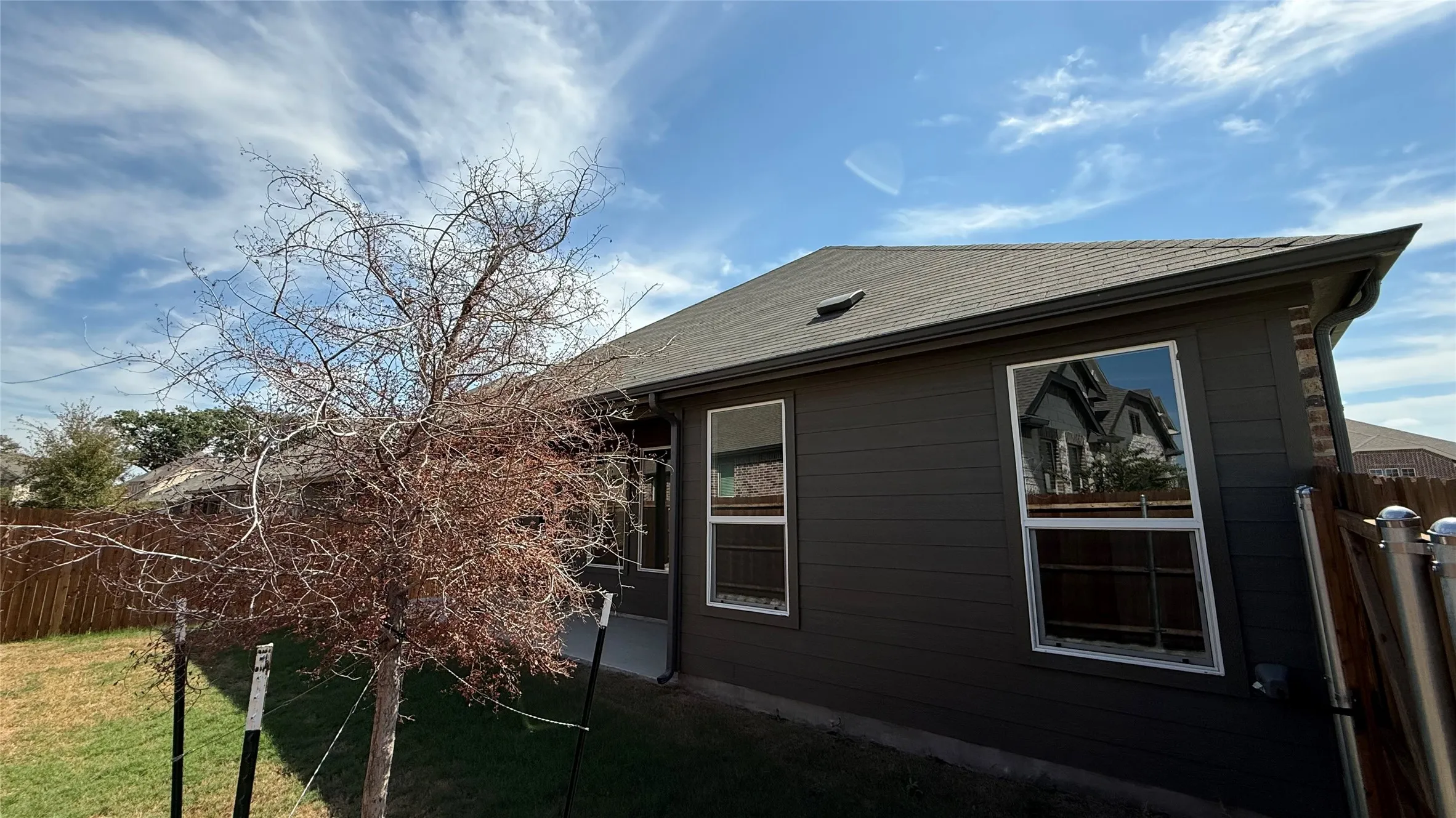 Dark-toned siding, white-framed windows, and a shingled roof