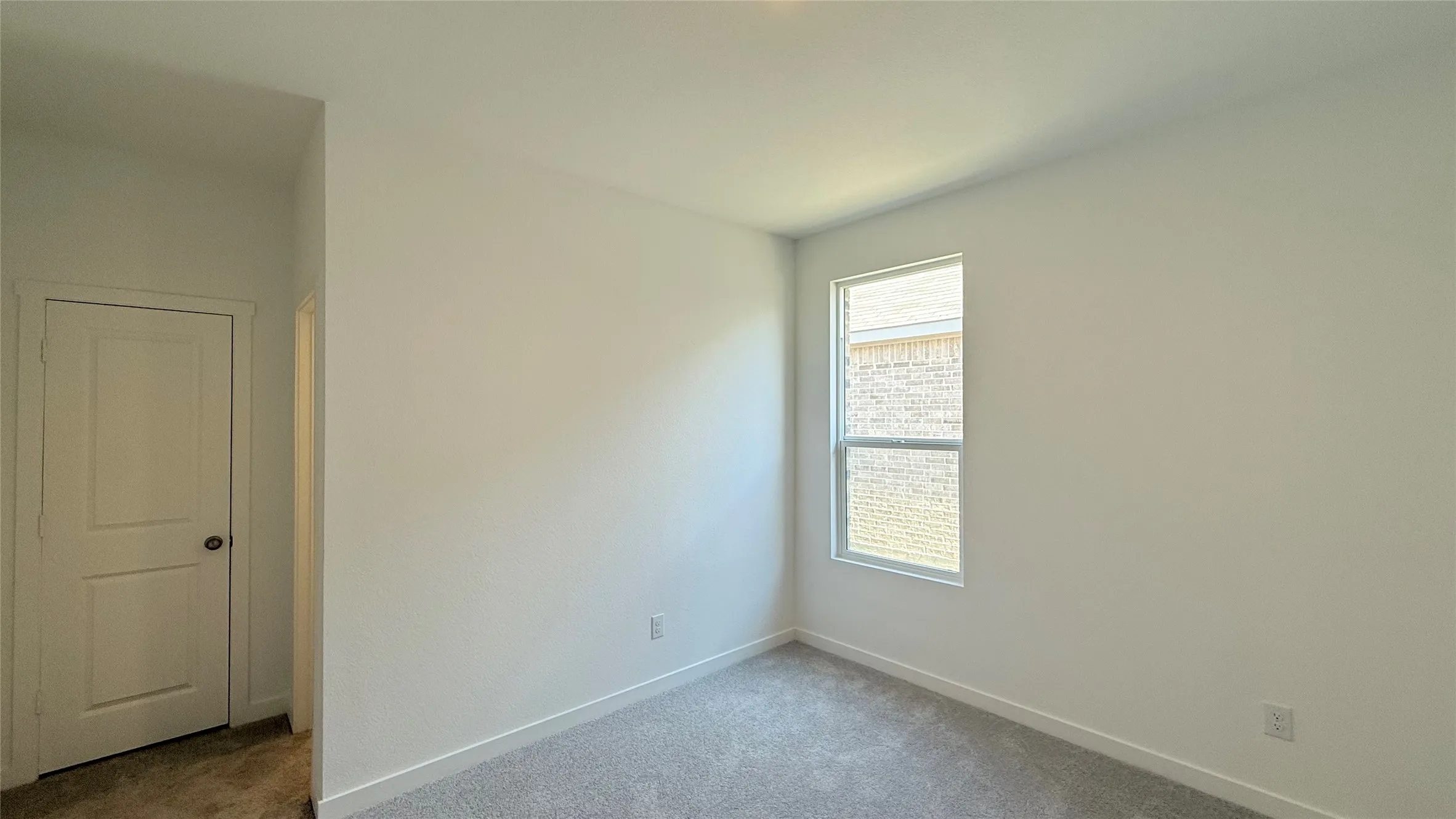 White walls, gray carpeting, and a single window with white trim