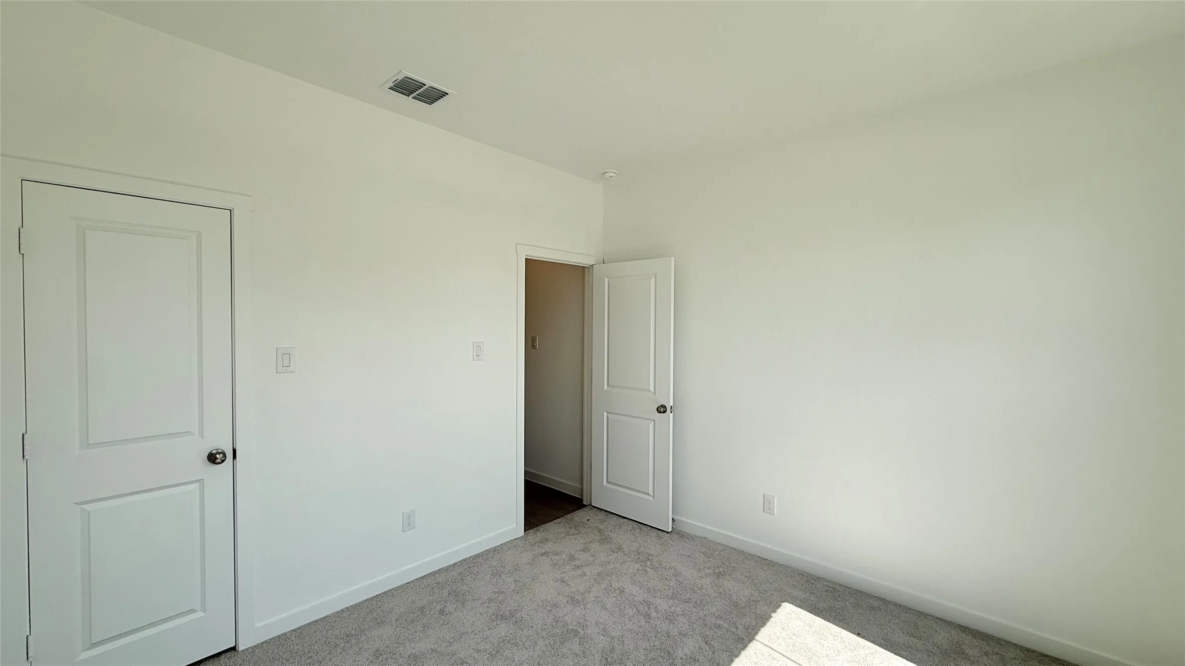 Neutral wall color with plush carpet flooring, featuring a solid panel interior door