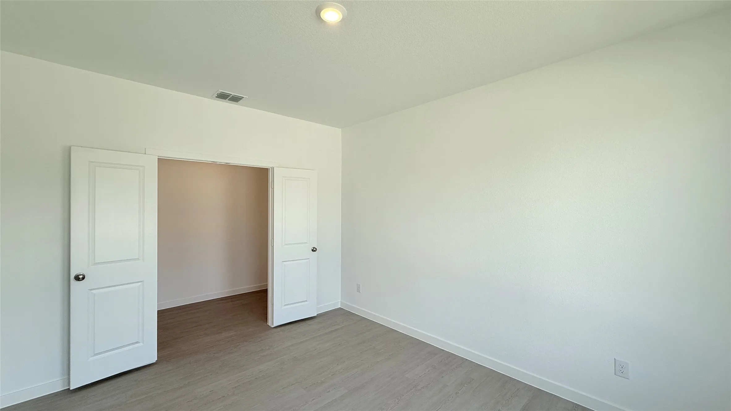 Recessed lighting, light wood-finish flooring, white walls, and a double door entry