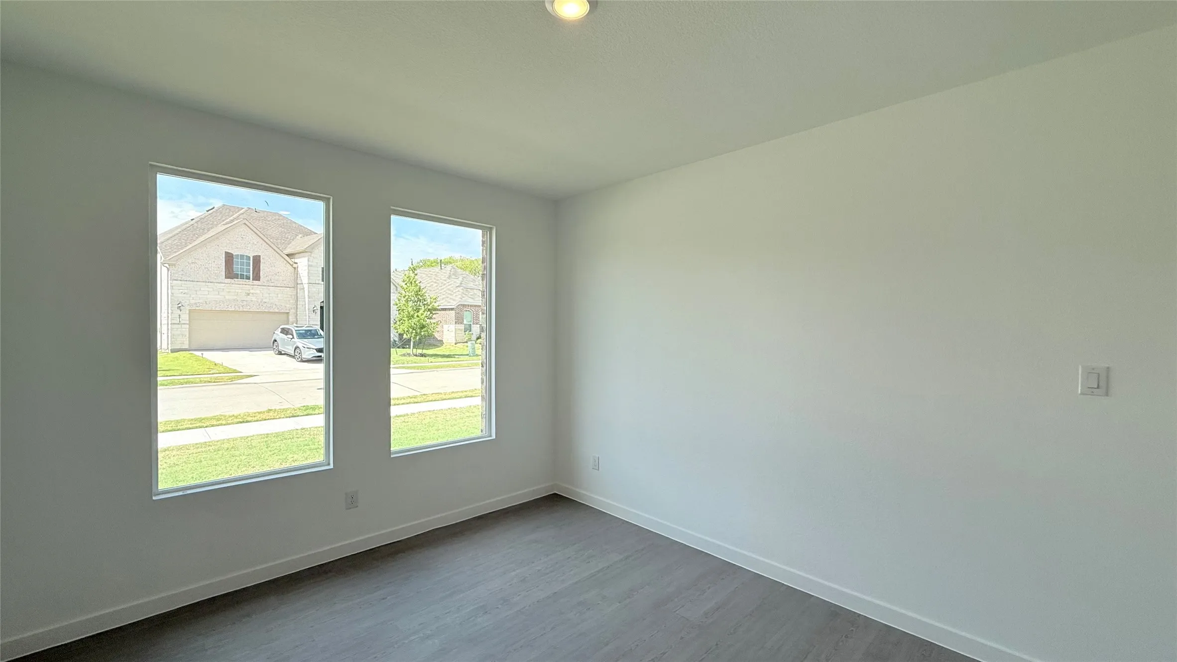 Neutral wall color, wood-finish flooring, two rectangular windows, and a ceiling-mounted light fixture