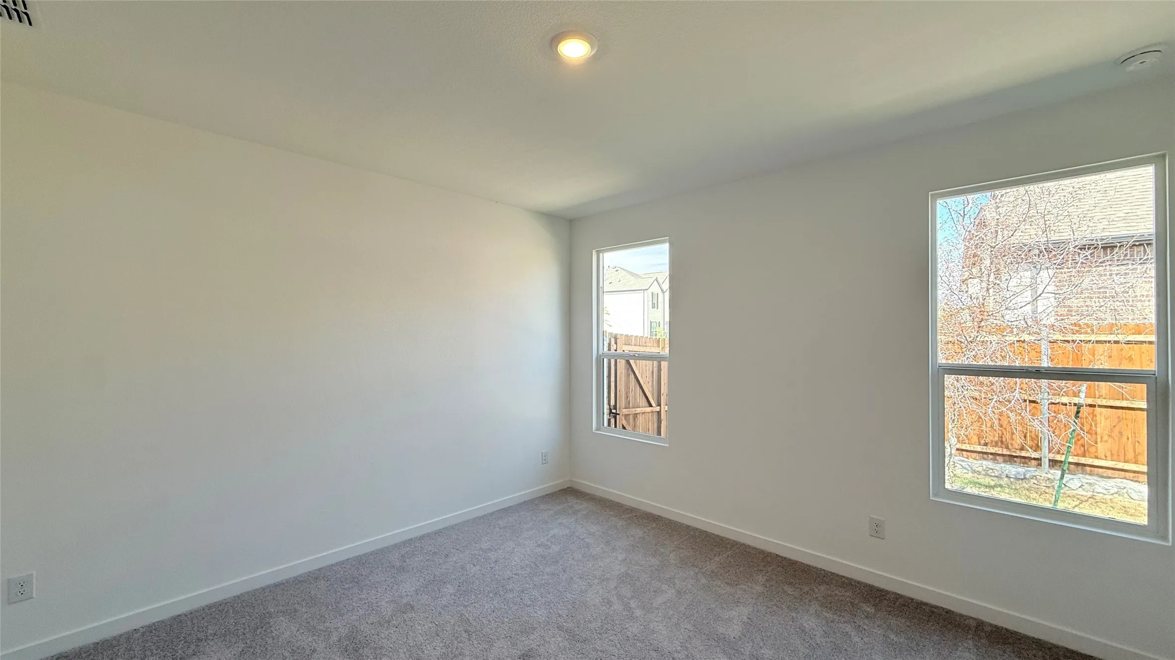 Recessed ceiling lighting, white walls, two windows, wall-to-wall carpeting, and white trim