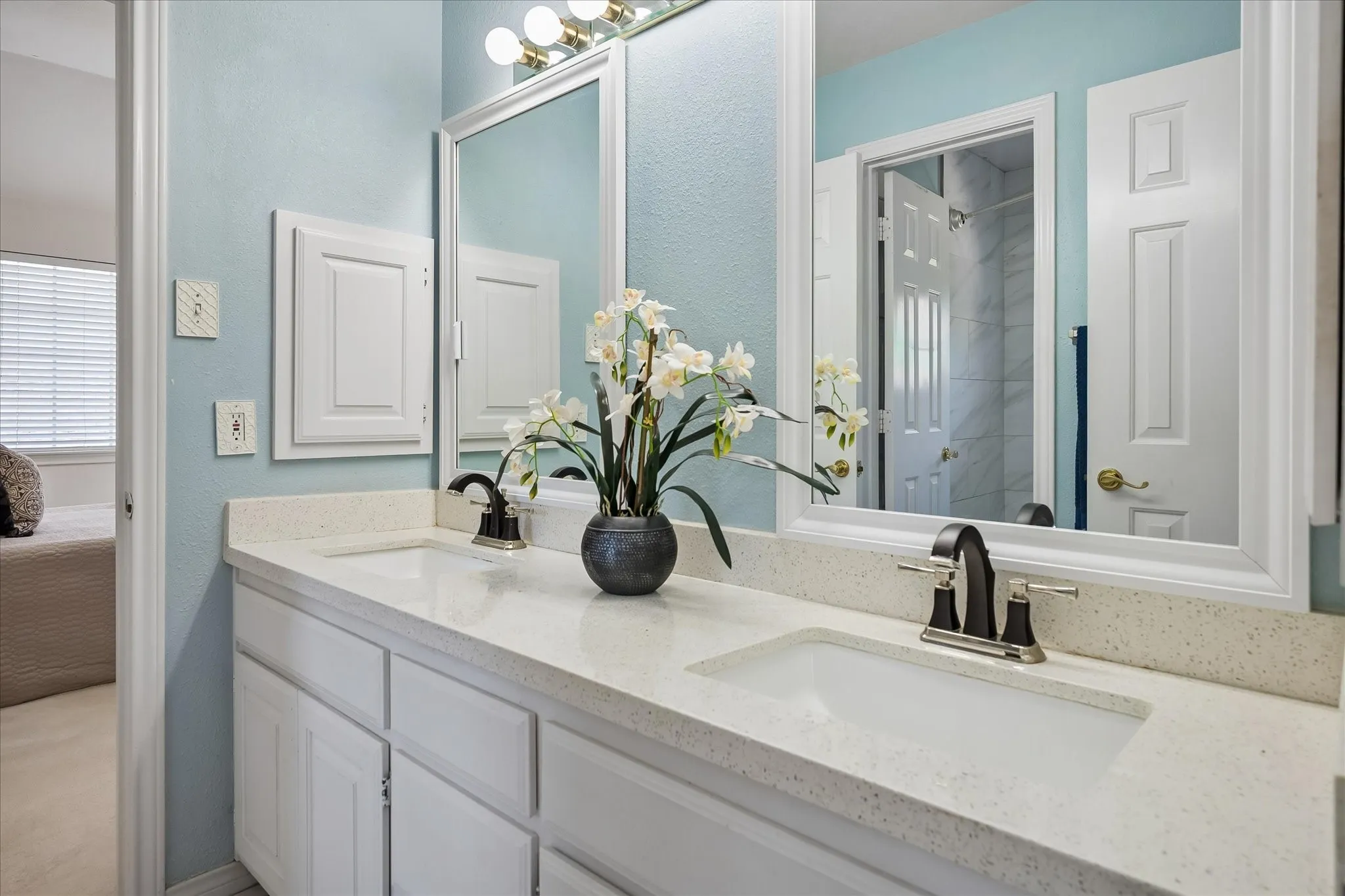 Dual vanity with undermount sinks, quartz countertops, and white cabinetry with dual medicine cabinets for additional storage