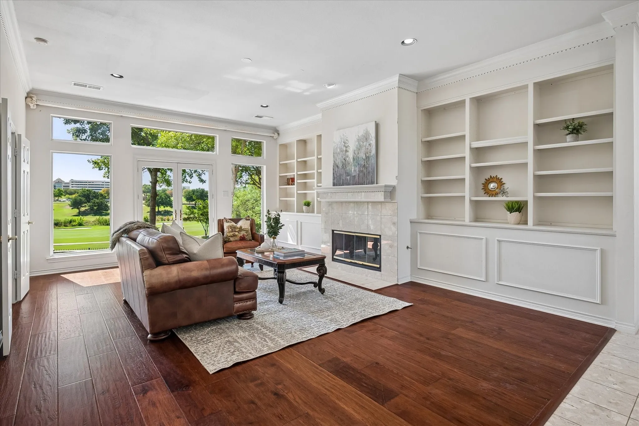 Wide plank American Hickory floors throughout, built-in shelving, tile-surround fireplace, crown molding, and expansive windows with outdoor access