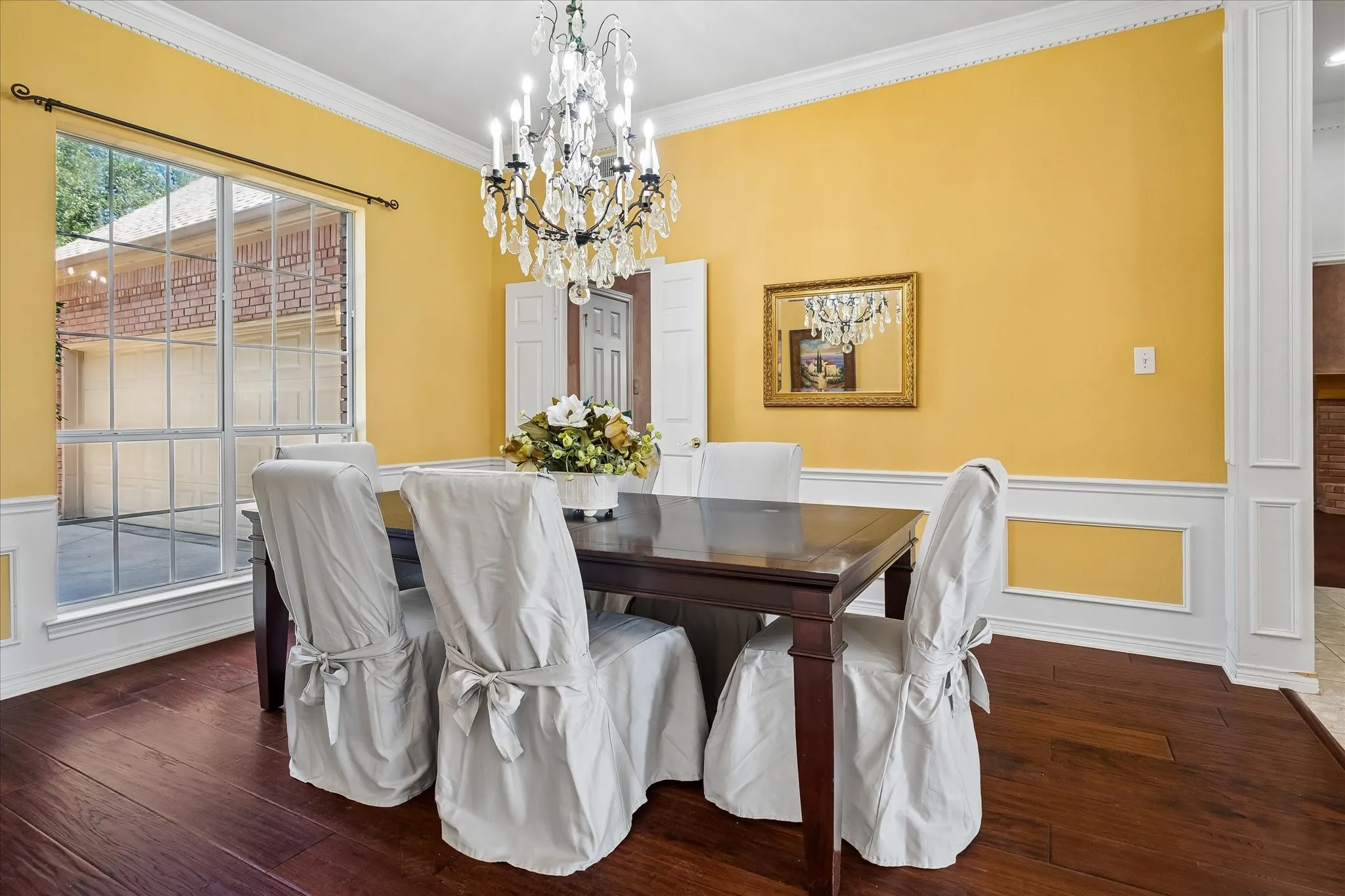 Hardwood flooring, decorative wainscoting, dental crown molding, and a sparkling crystal chandelier