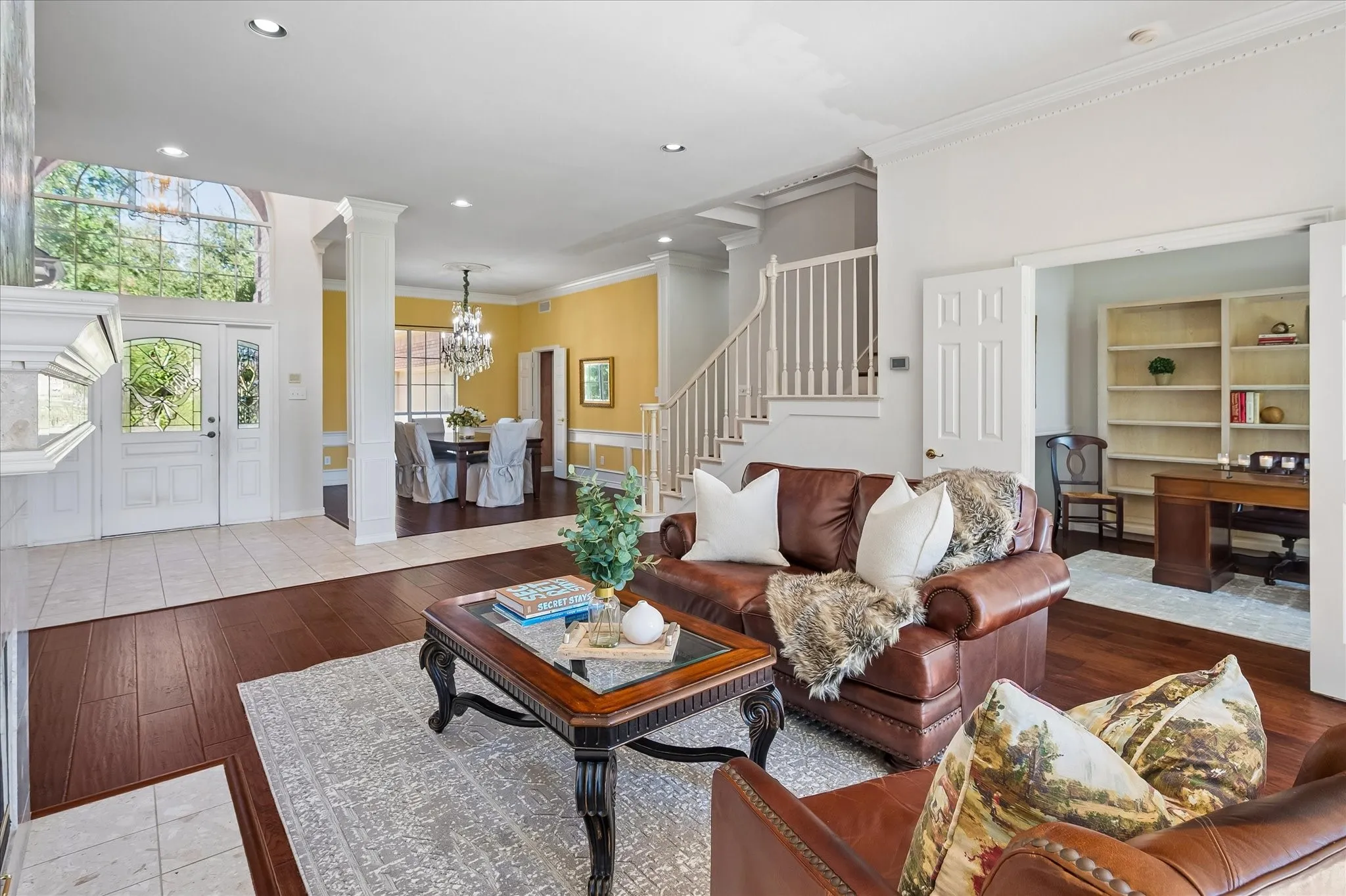 Terrazzo tile and American Hickory hardwood flooring throughout, a grand entry with decorative glass doors, a formal dining area with a chandelier, and a dedicated office space with built-in shelving