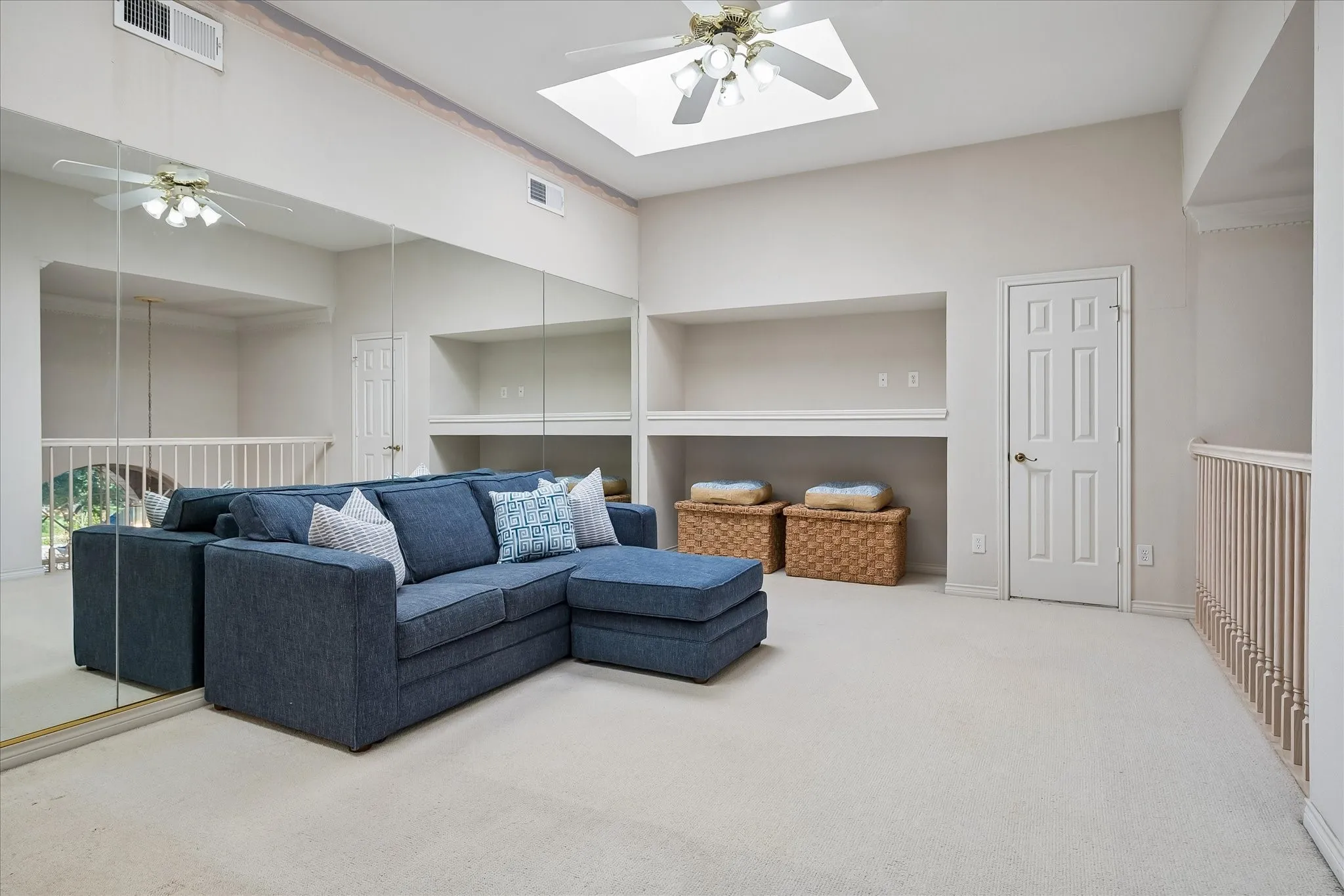 Recessed ceiling skylights, ceiling fan with integrated lighting, full-wall mirrors, built-in shelving, and neutral carpeting with walk out attic access