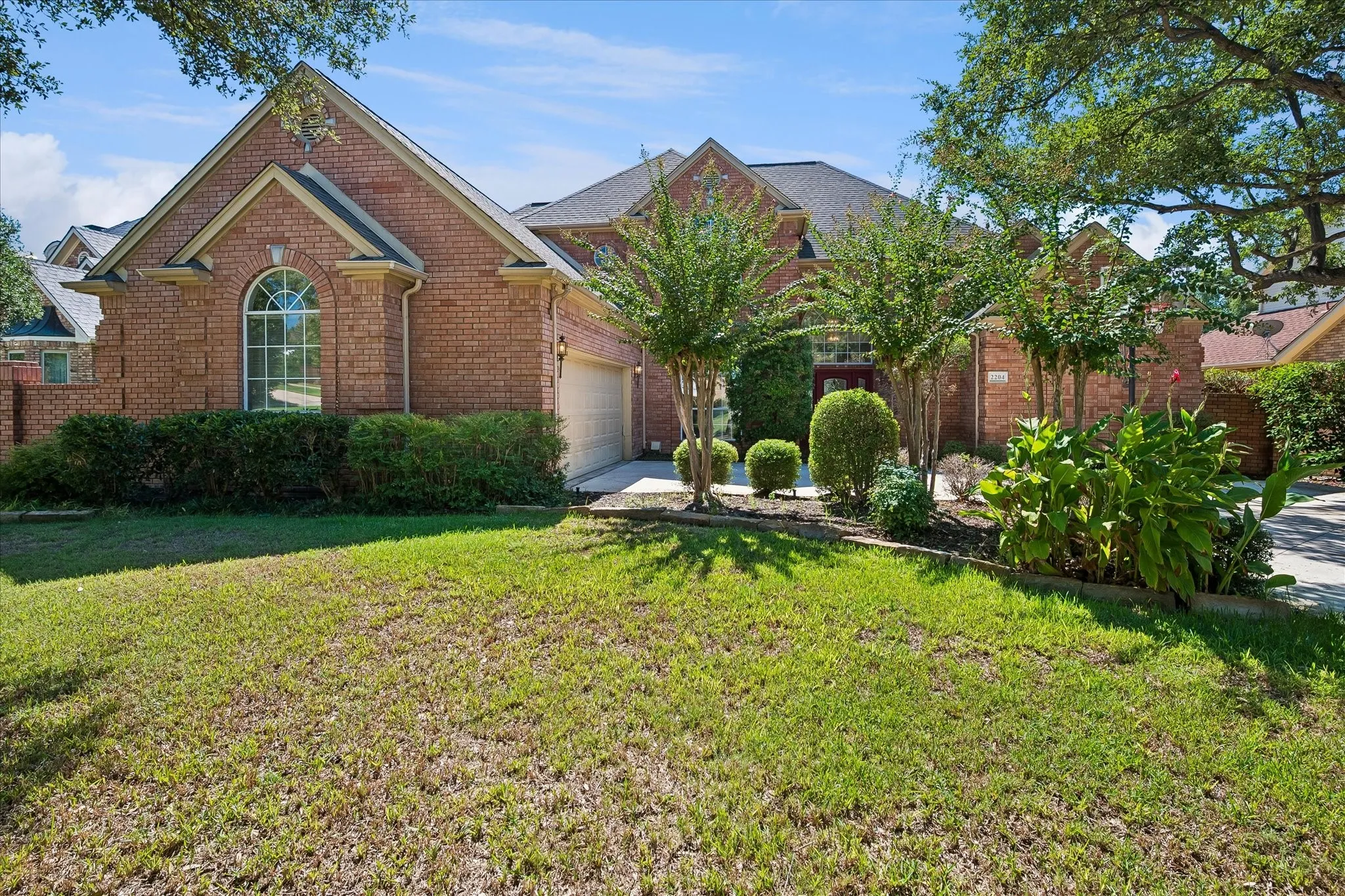 Brick exterior featuring a gabled roofline, arched window, and attached garage