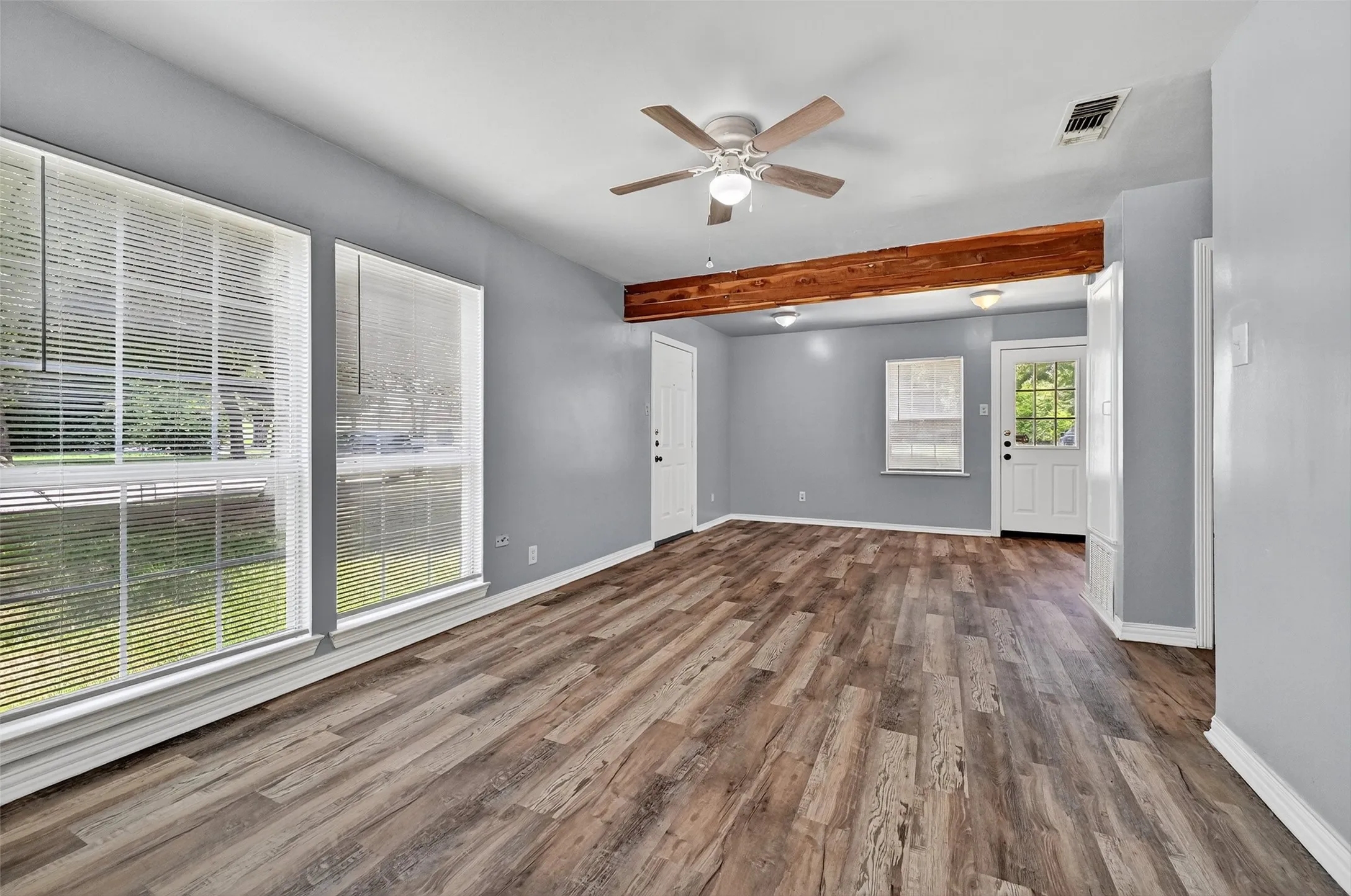 Unfurnished room featuring beam ceiling, wood finished floors, and a ceiling fan