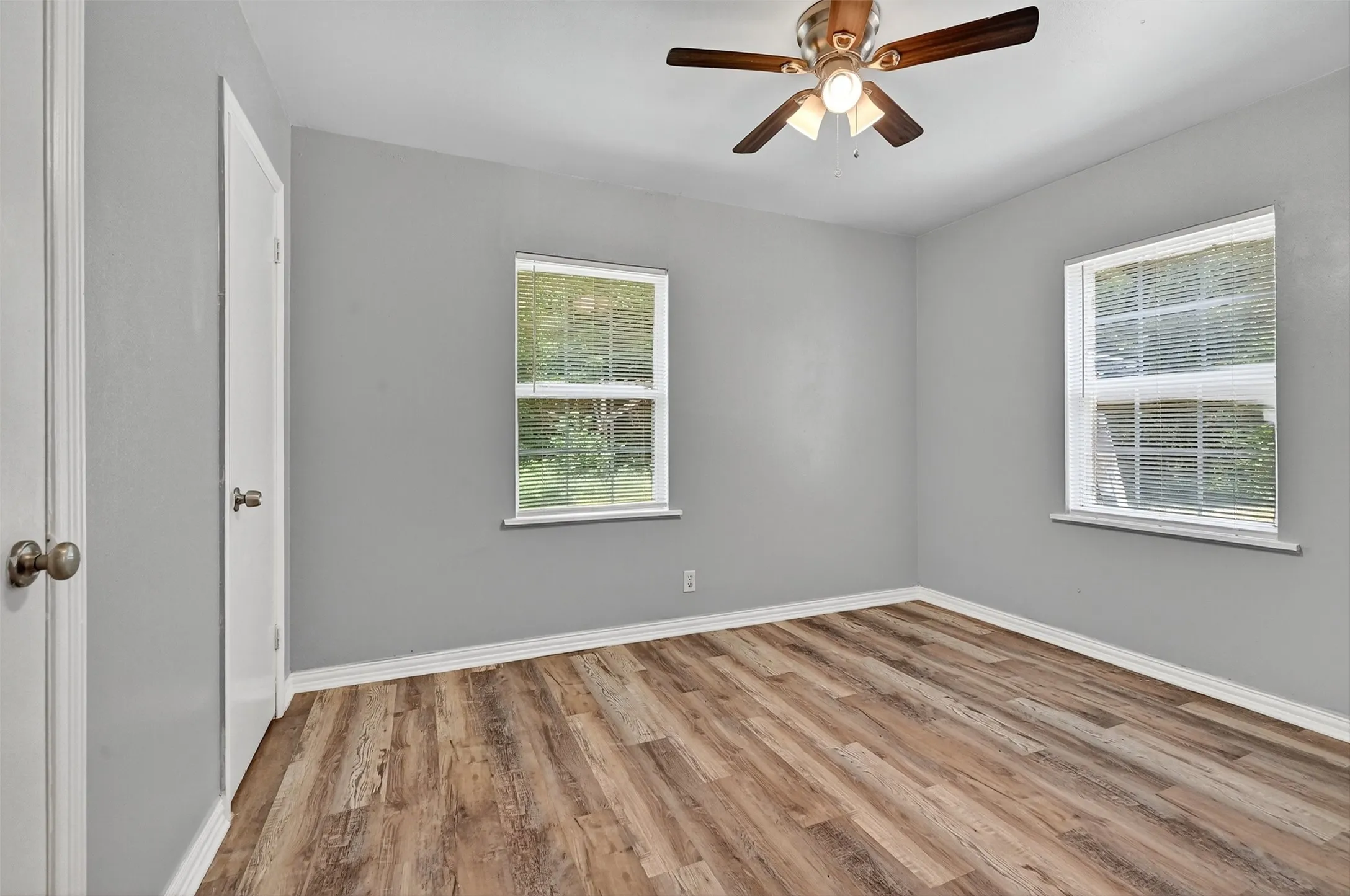 Empty room featuring healthy amount of natural light, wood finished floors, and a ceiling fan