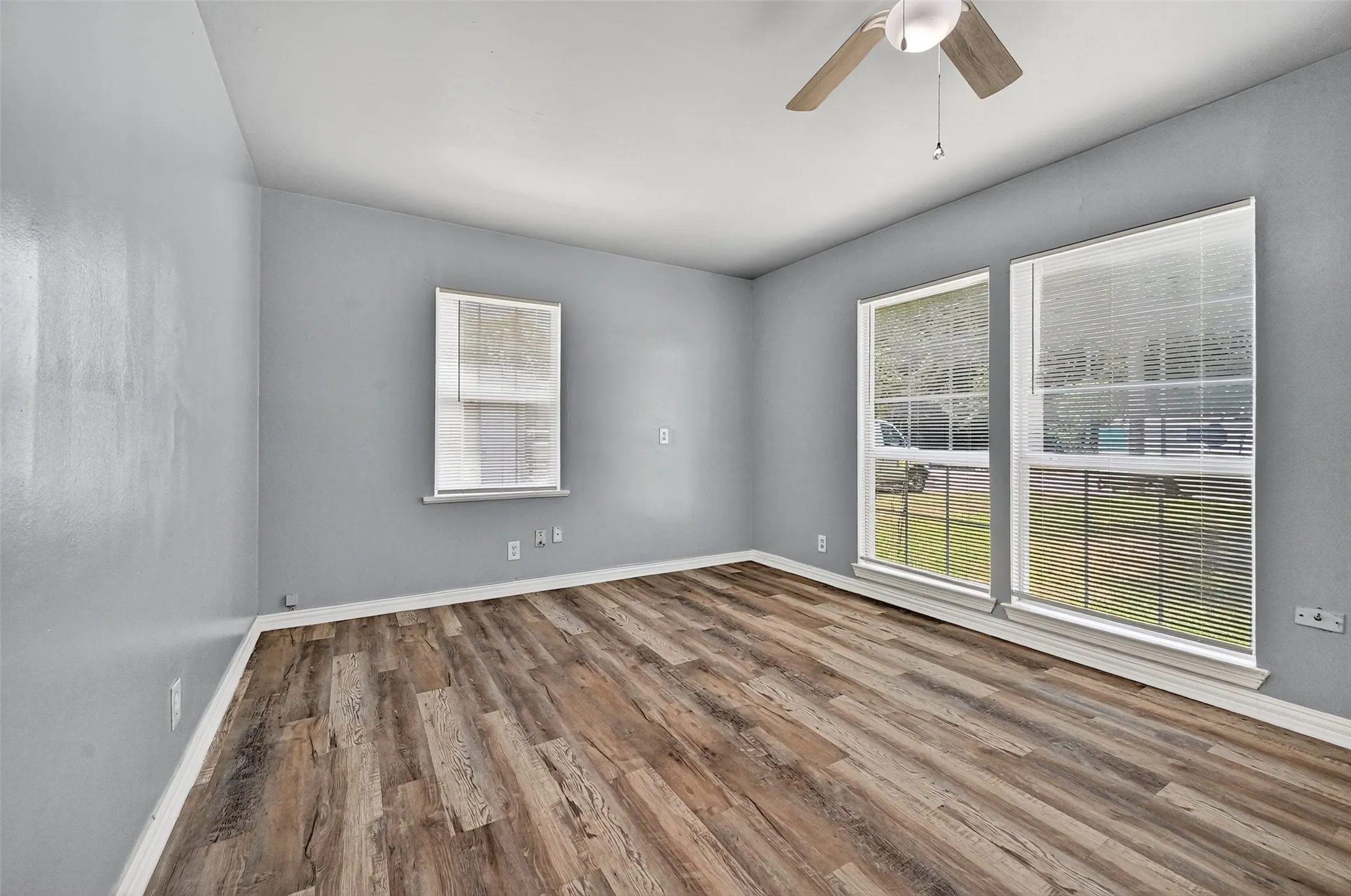 Empty room with healthy amount of natural light, wood finished floors, and a ceiling fan