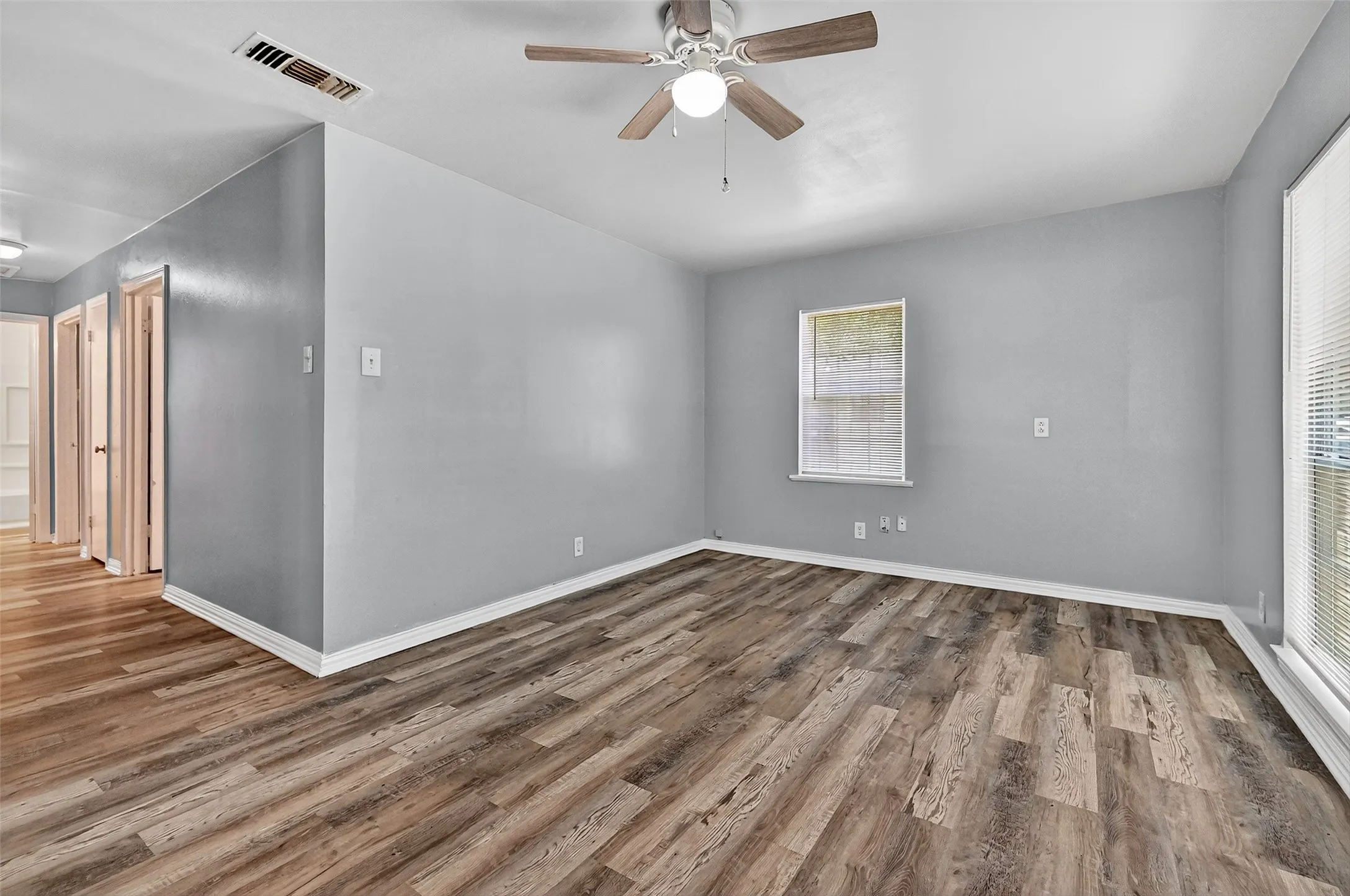 Unfurnished room with wood finished floors, ceiling fan, and plenty of natural light