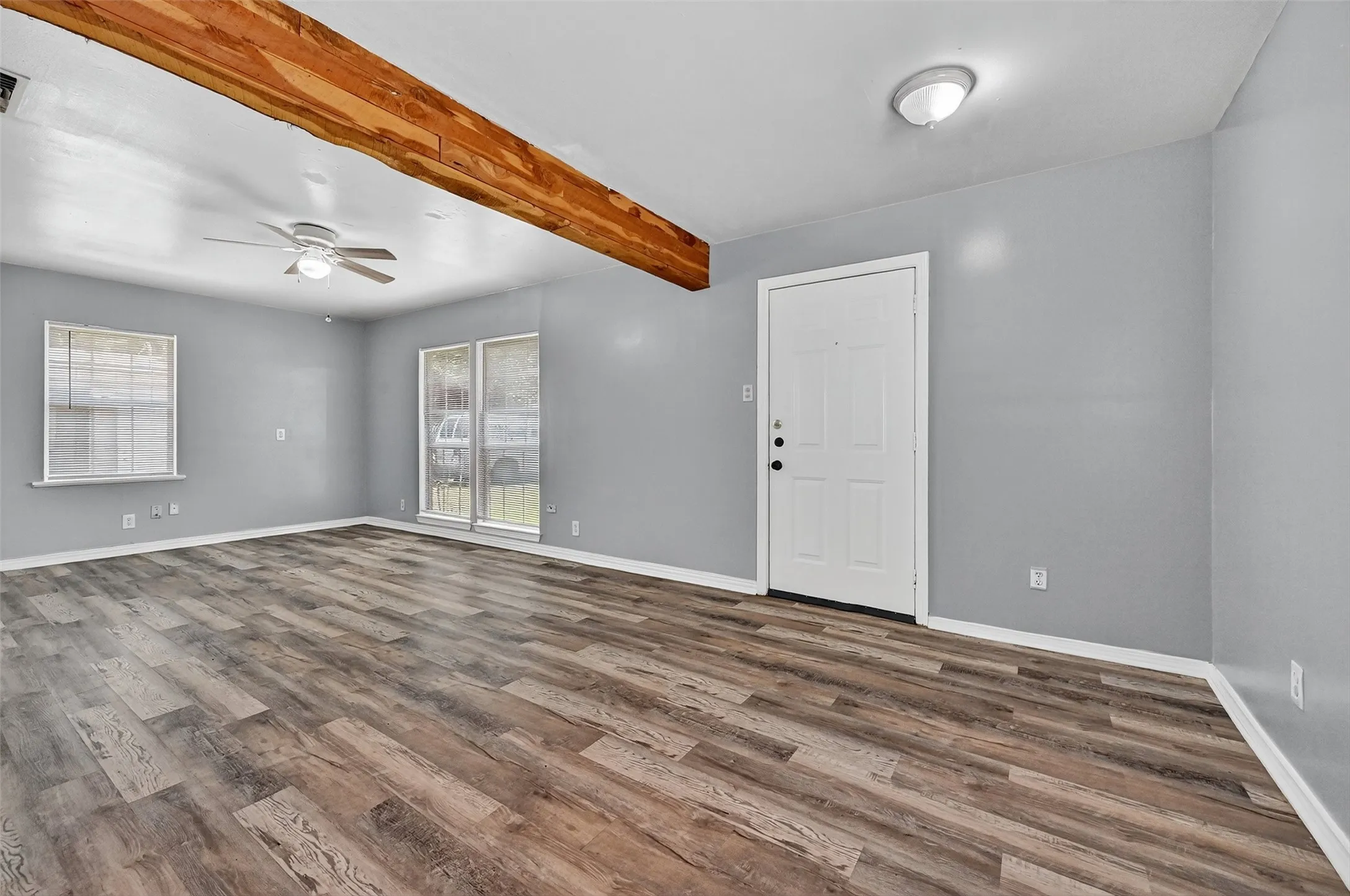 Unfurnished room featuring ceiling fan, beamed ceiling, and dark wood finished floors