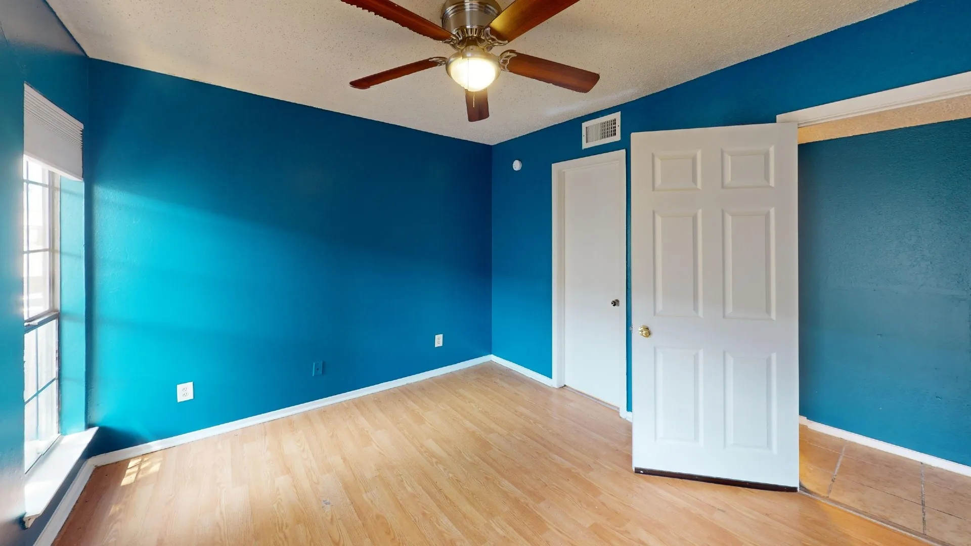 Room featuring wood-finish flooring, a ceiling fan with integrated lighting, and multiple windows
