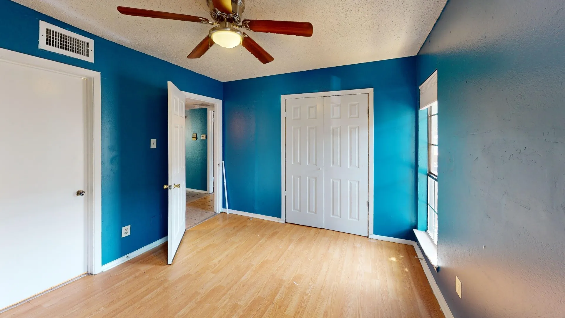 Wood-finish flooring, ceiling fan, bi-fold closet doors, and window with natural light