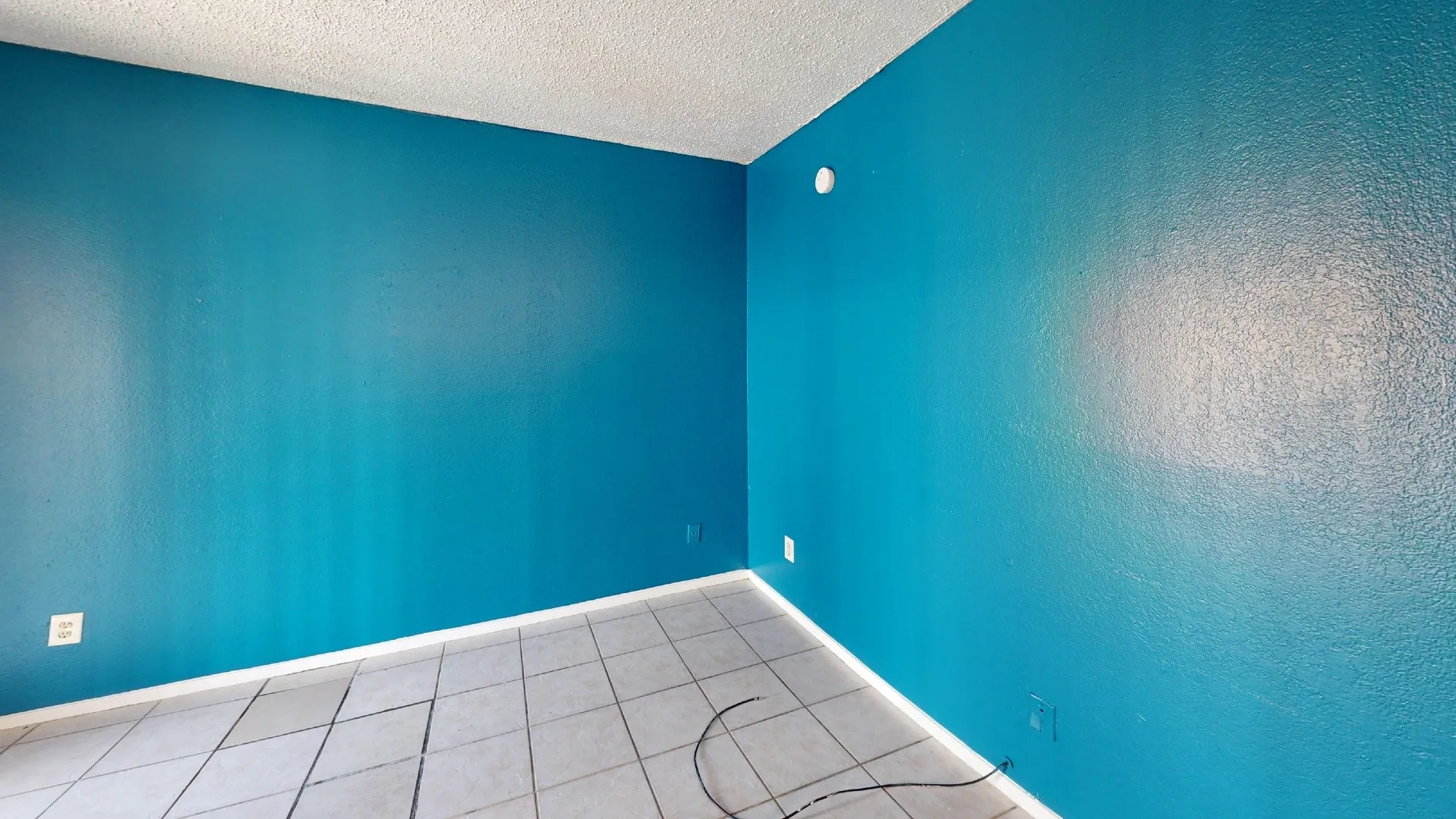 Textured walls with a vibrant blue finish, white ceiling, and light-toned tile flooring