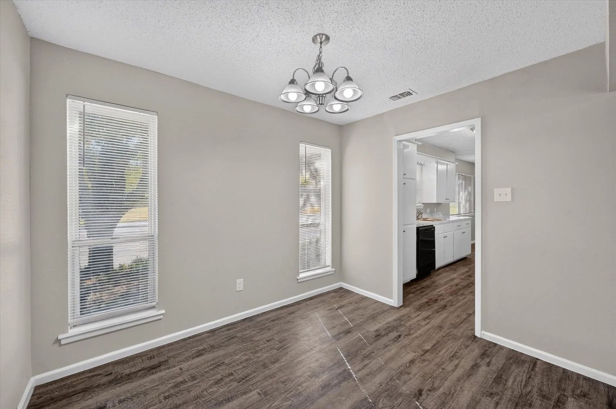 Wood-finish flooring with neutral wall paint, two vertical windows, and a ceiling-mounted light fixture