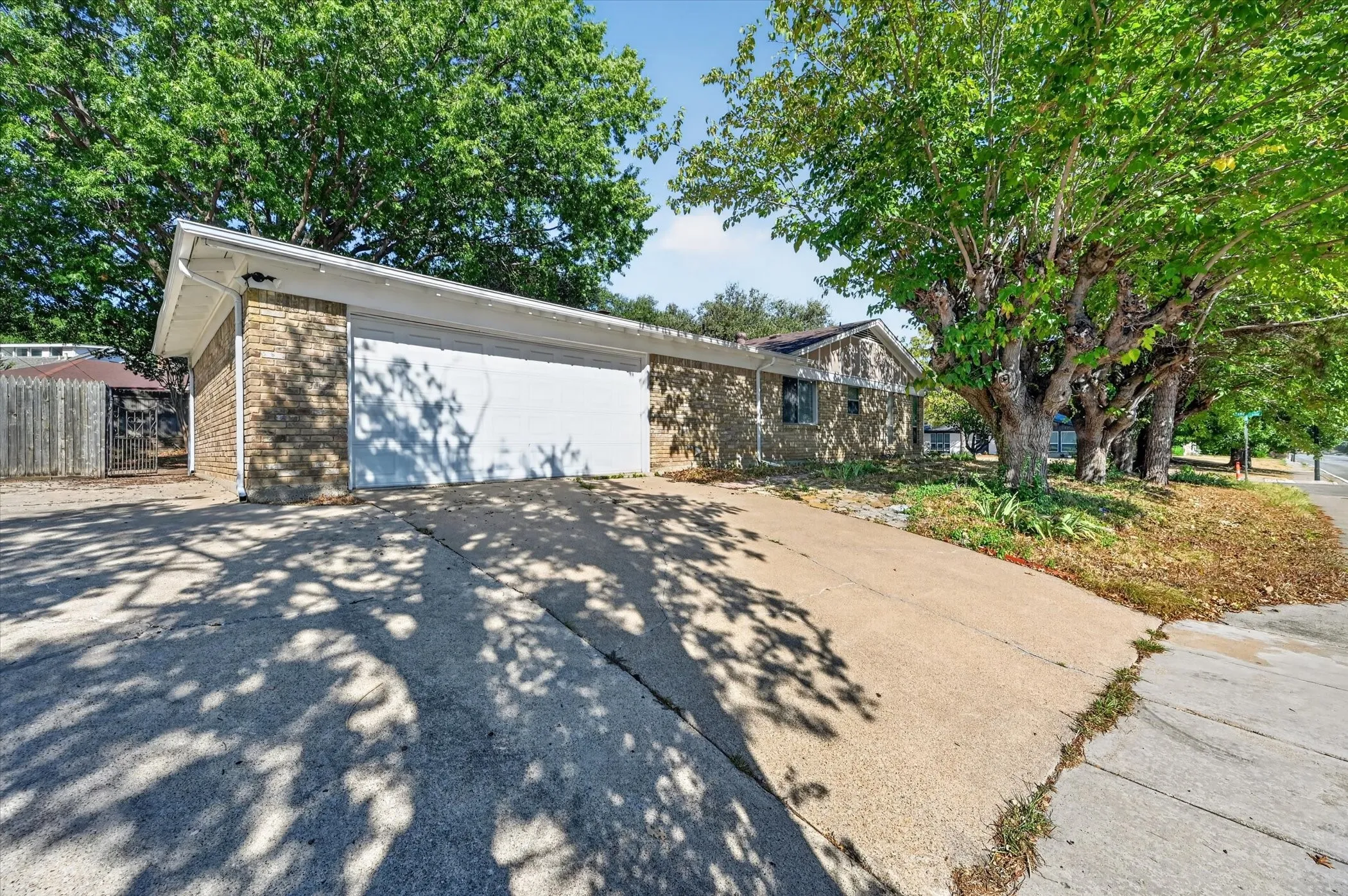 Attached two-car garage with a white overhead door, brick exterior, and concrete driveway