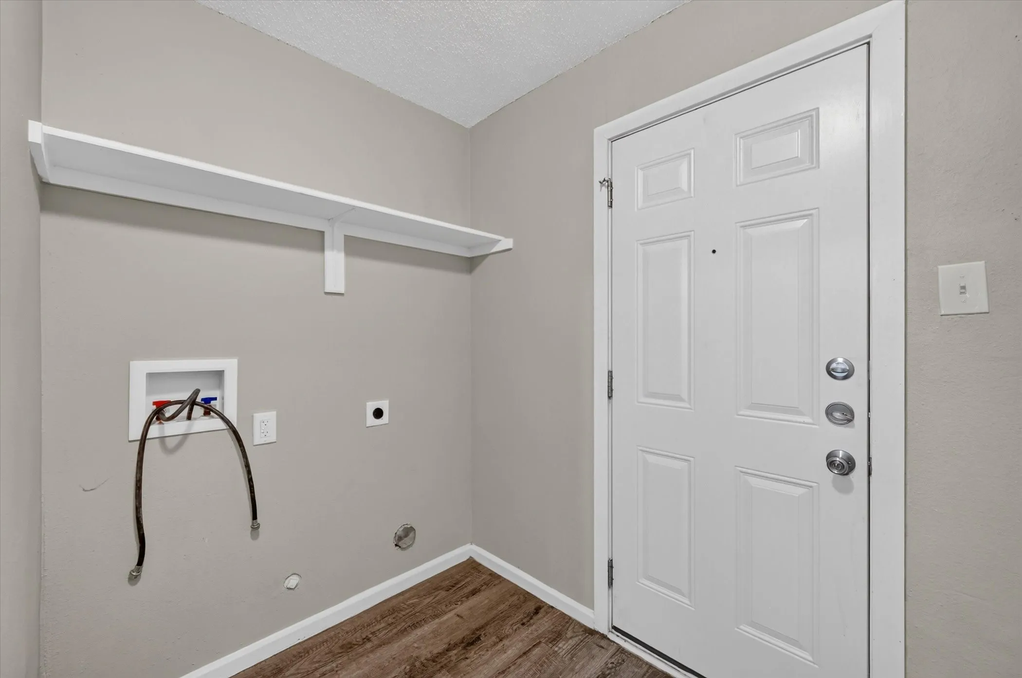 Laundry area featuring a built-in shelf, wood-finish flooring, and a paneled entry door