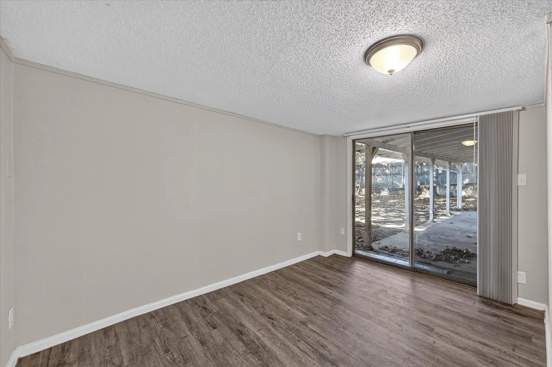 Wood-finish flooring, neutral wall paint, and sliding glass doors to outdoor concrete patio