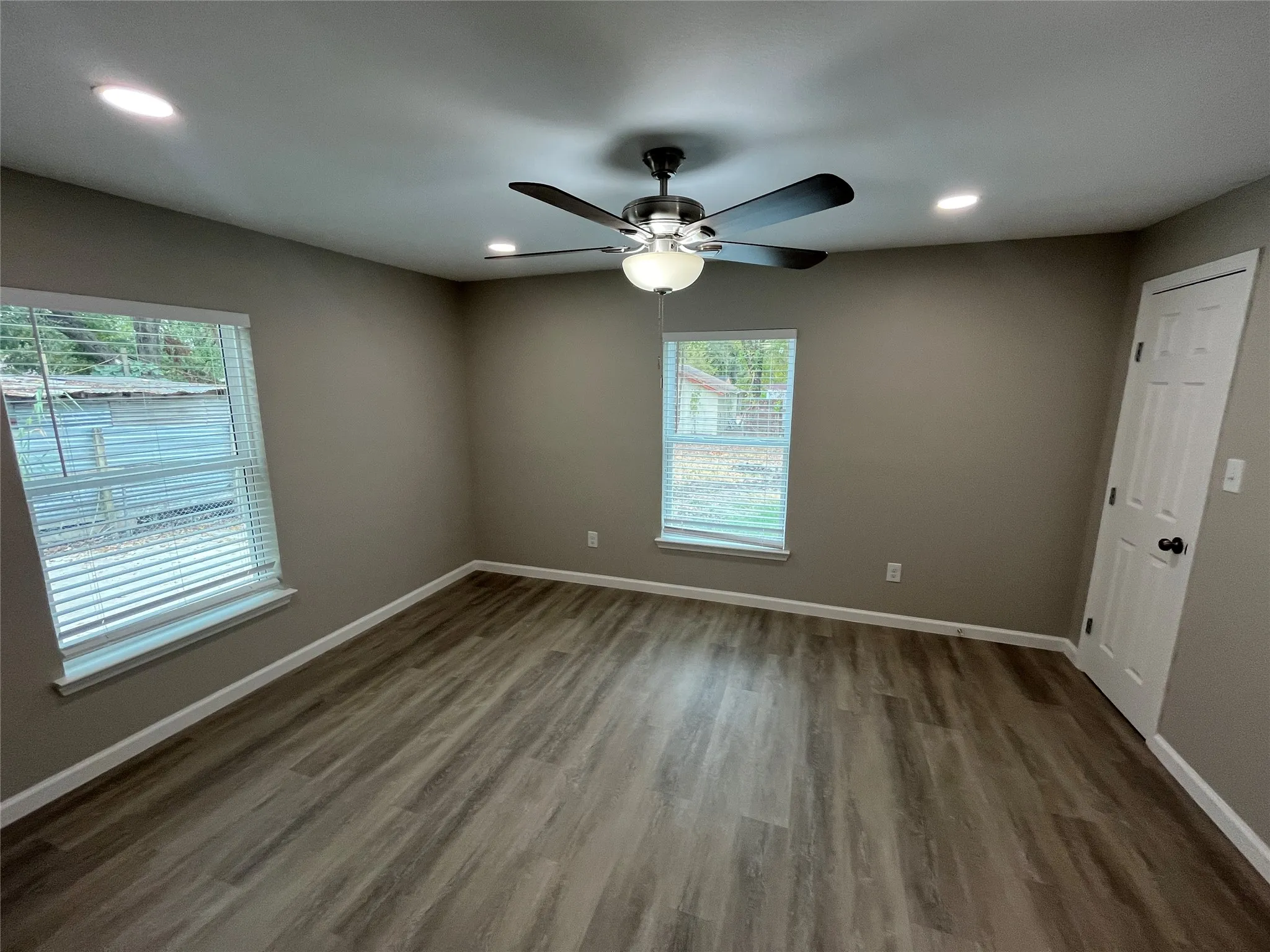 Recessed lighting, wood-finish flooring, ceiling fan with integrated light, window treatments, and a paneled interior door