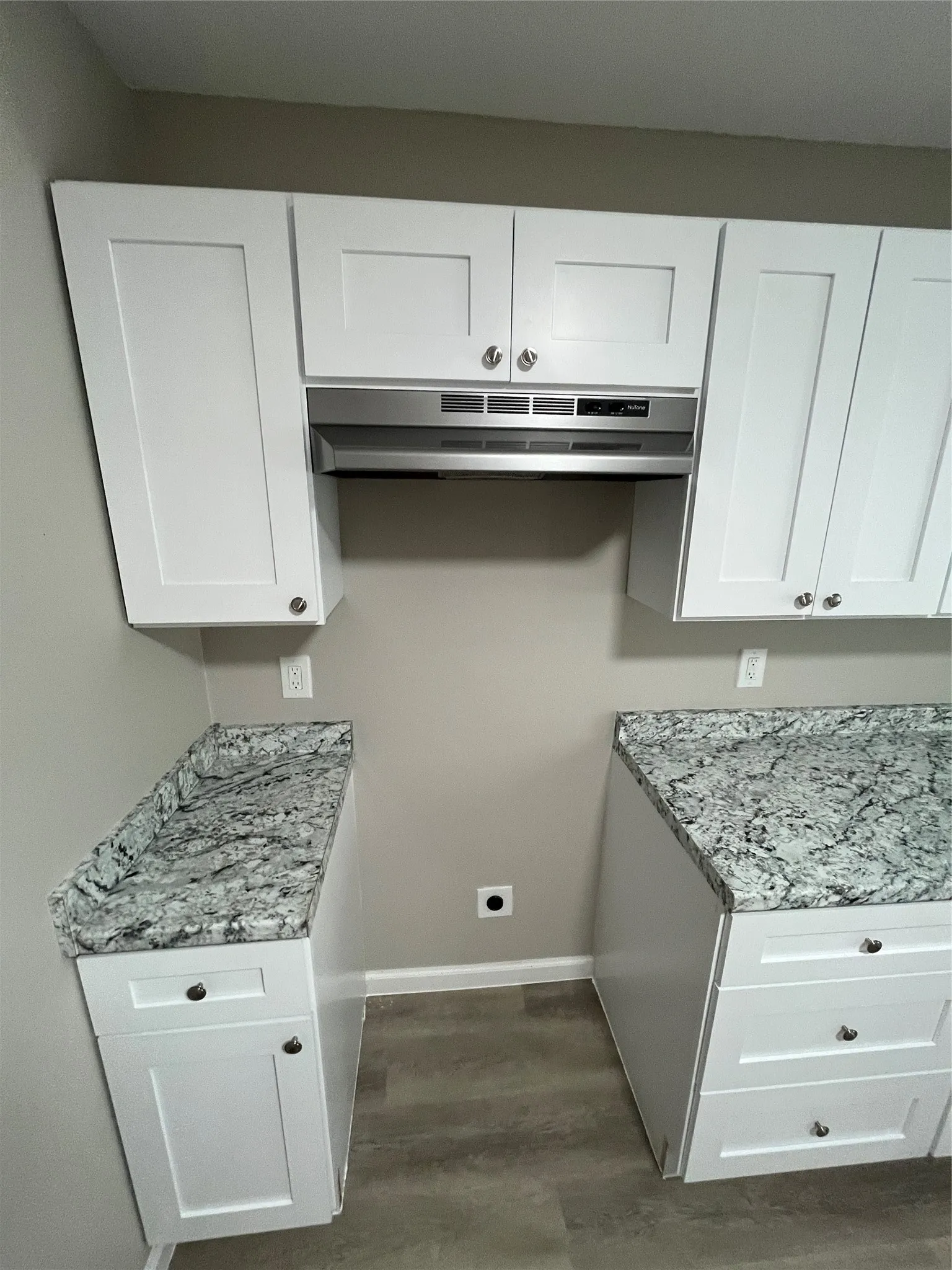 White shaker-style cabinetry with chrome hardware, stone countertops, and wood-finish flooring