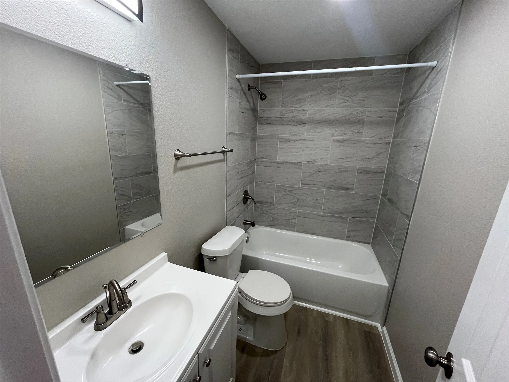 Bathroom featuring a vanity with an integrated sink, brushed nickel faucet, a mirror, and a shower-tub combination with tile surround