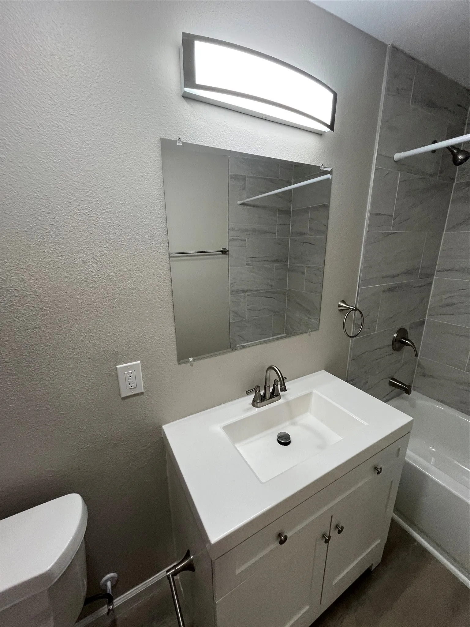 White vanity with an integrated sink, brushed nickel faucet, and a wall-mounted mirror