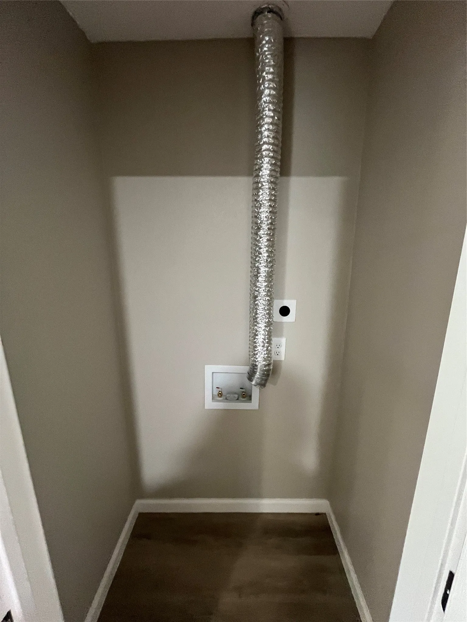 Utility closet with wood-finish flooring, neutral wall paint, and laundry hookups