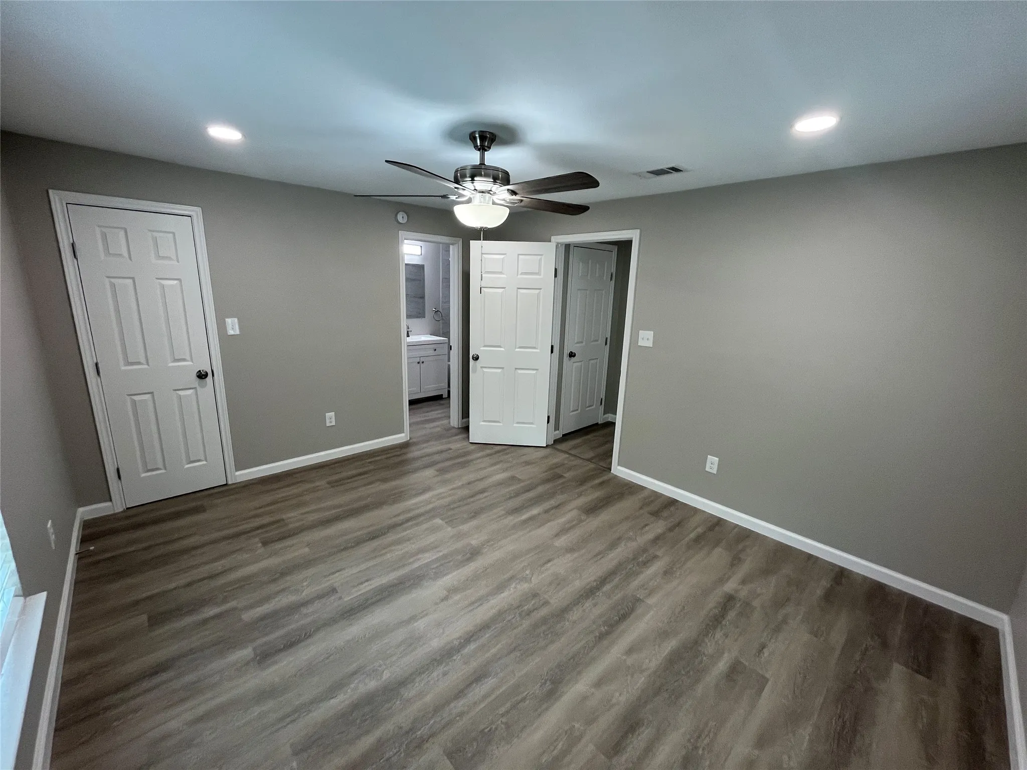 Wood-finish flooring, recessed lighting, ceiling fan with integrated light, and white paneled doors