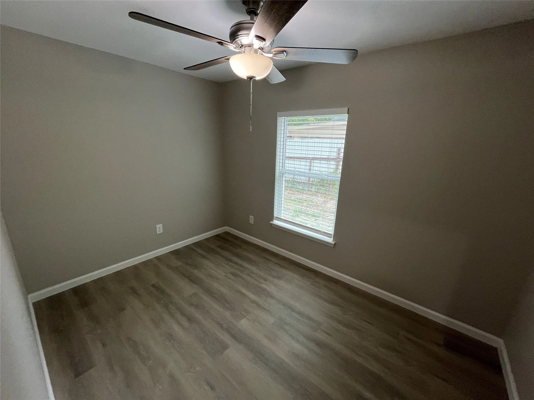 Wood-finish flooring, neutral wall tones, and a ceiling fan with integrated lighting